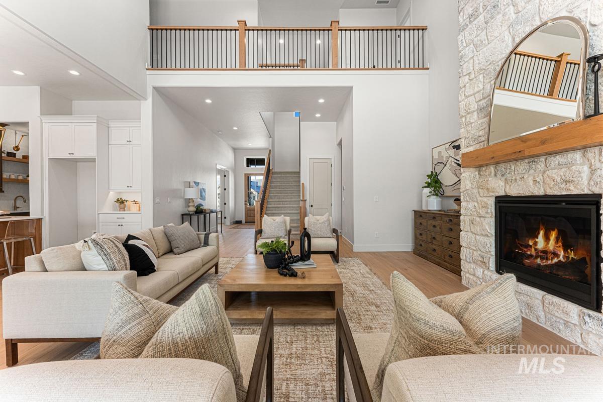 Living area with a fireplace, light wood-style flooring, a high ceiling, and recessed lighting