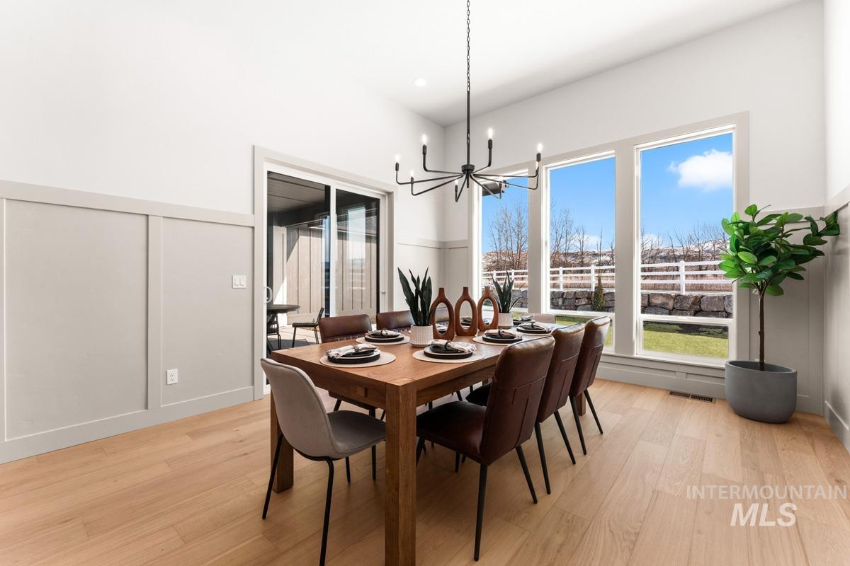 Dining area featuring light wood-style flooring, a decorative wall, and suspended lighting
