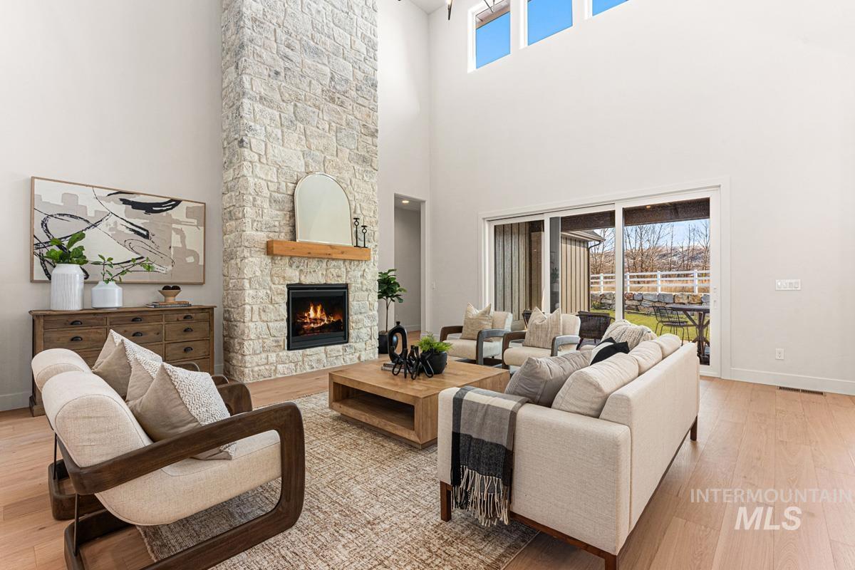 Living area featuring light wood-style flooring, a fireplace, and a high ceiling