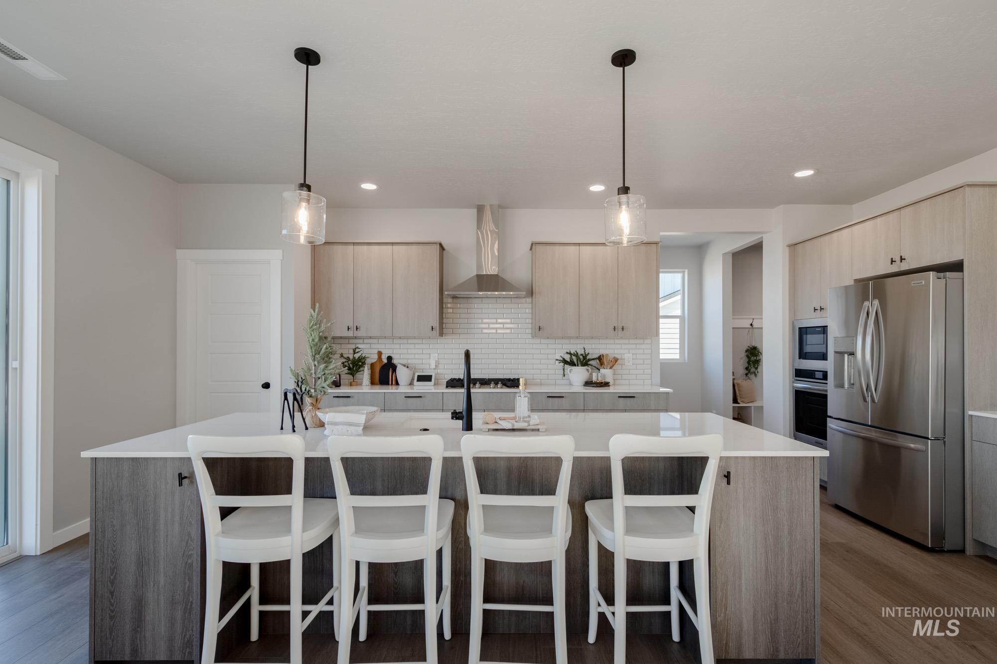 Kitchen with appliances with stainless steel finishes, an island with sink, a kitchen bar, decorative backsplash, and recessed lighting