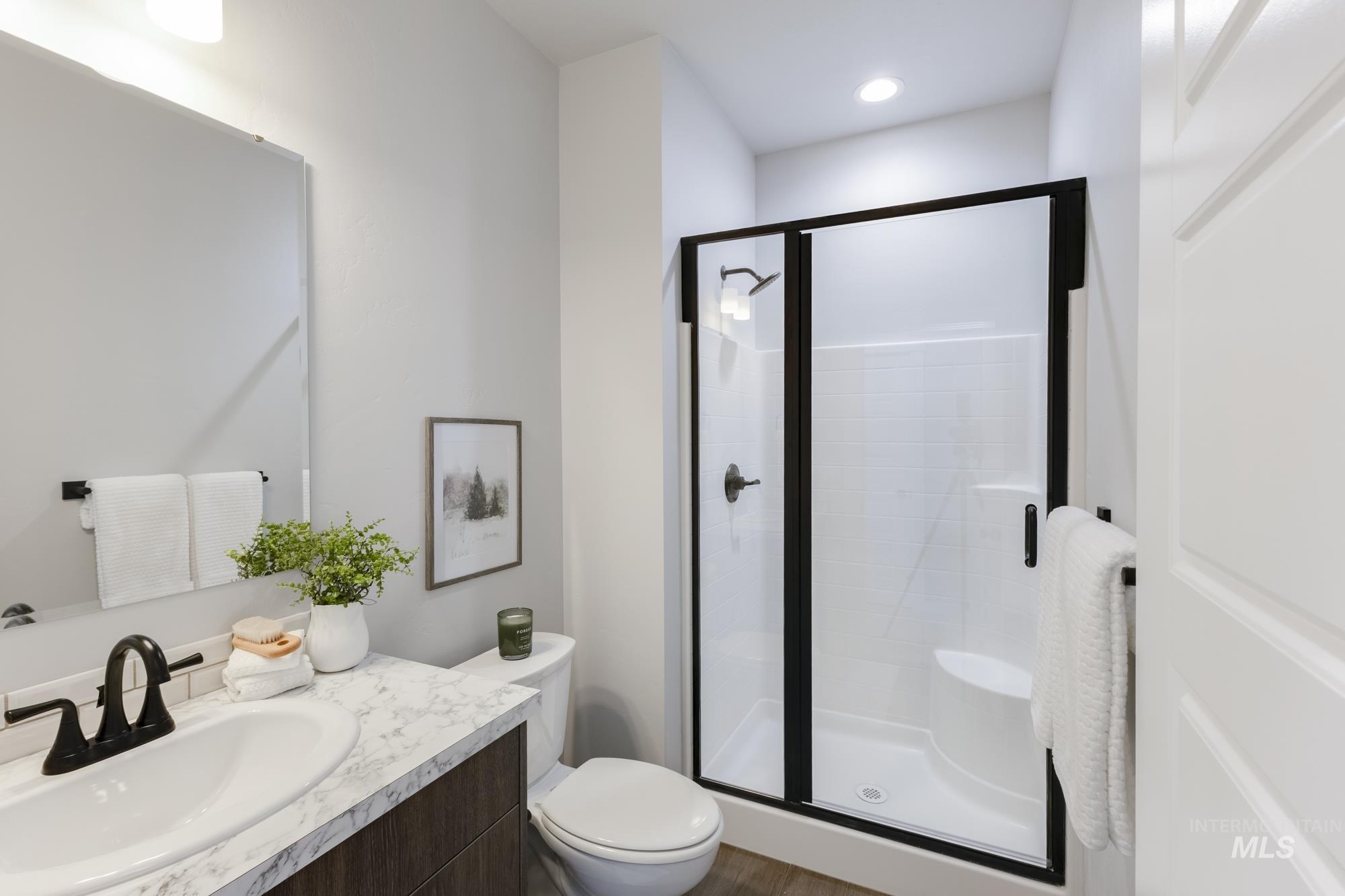 Bathroom with vanity, a stall shower, and wood finished floors