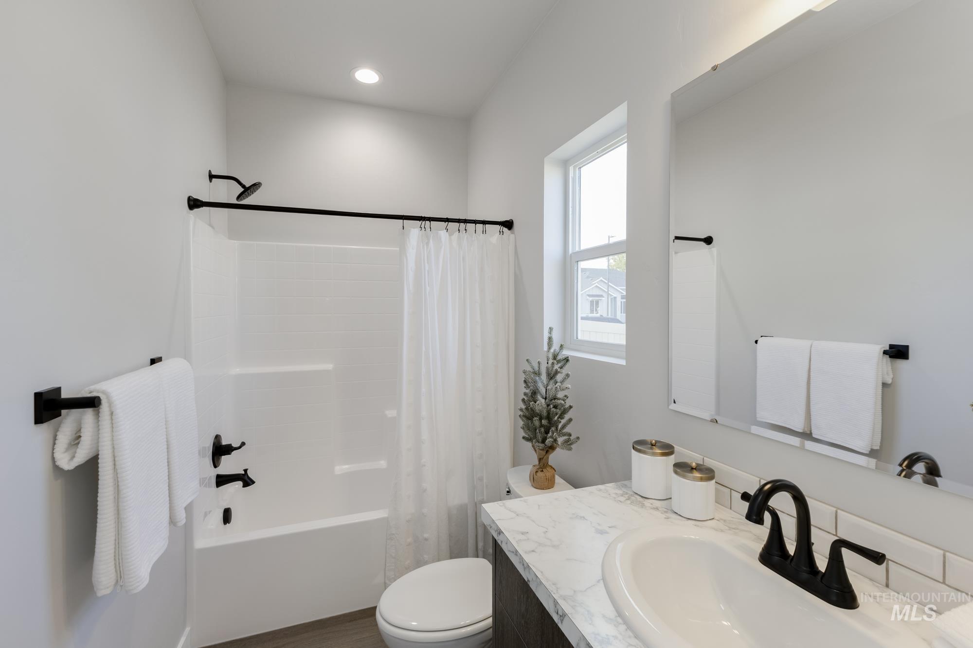 Full bath with shower / tub combo, vanity, and dark wood finished floors