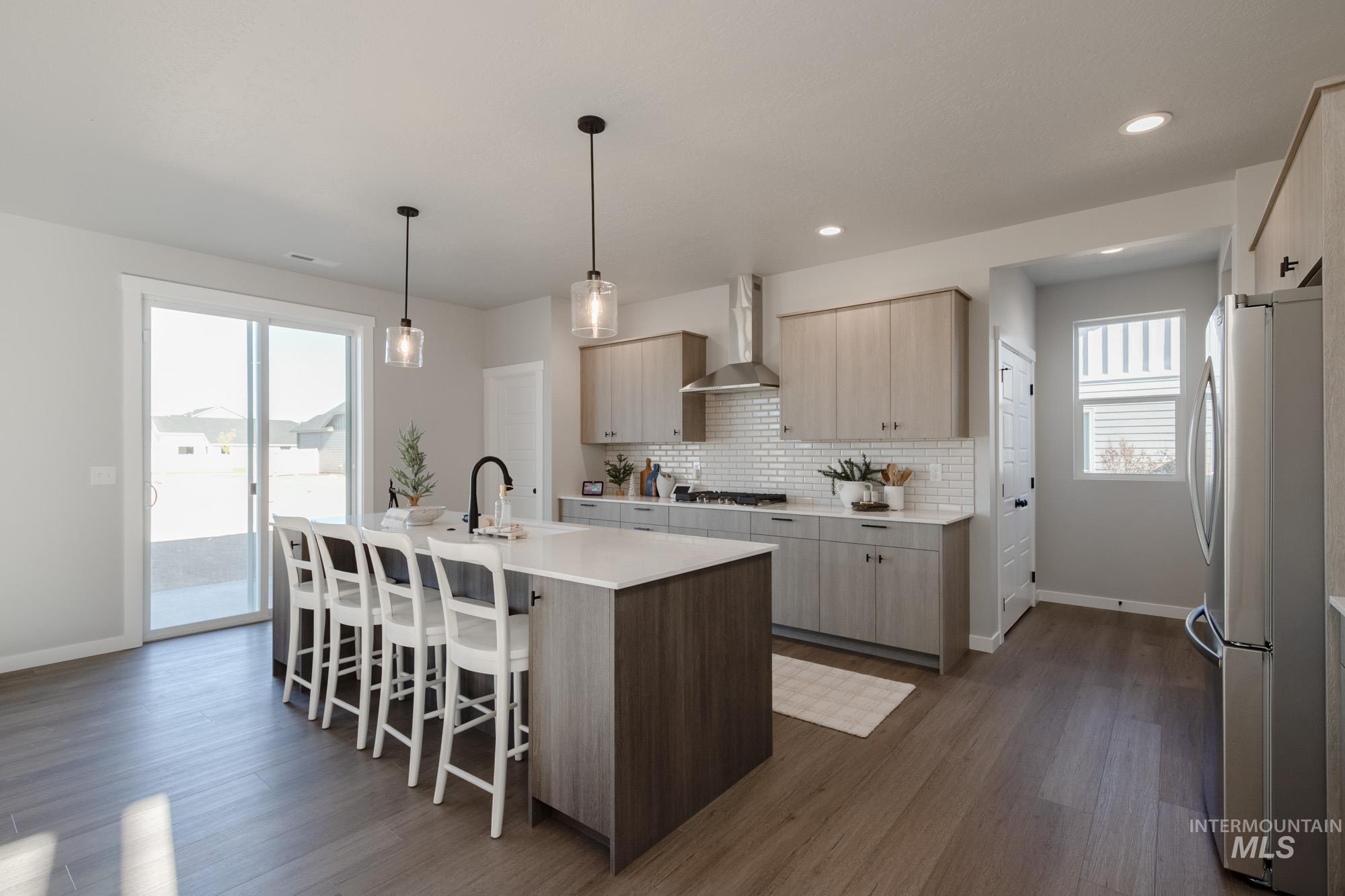 Kitchen featuring a kitchen bar, appliances with stainless steel finishes, tasteful backsplash, an island with sink, and dark wood-style floors