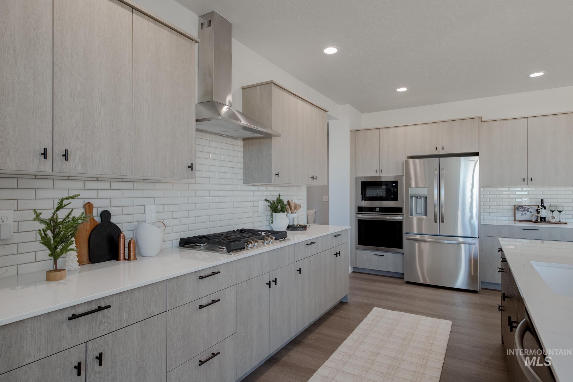 Kitchen featuring stainless steel appliances, wall chimney exhaust hood, tasteful backsplash, light brown cabinetry, and recessed lighting