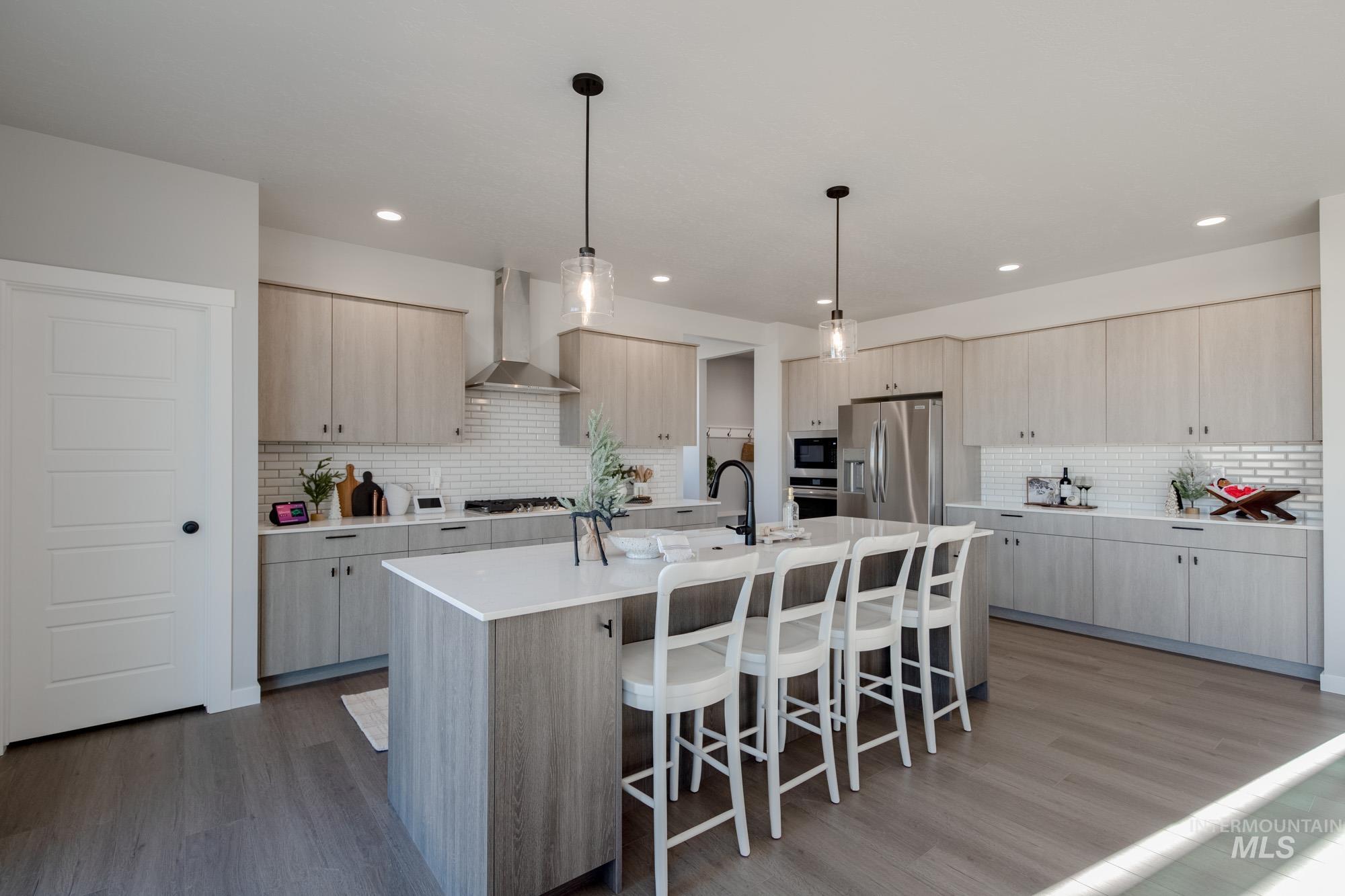 Kitchen featuring a breakfast bar, pendant lighting, light brown cabinets, a center island with sink, and backsplash