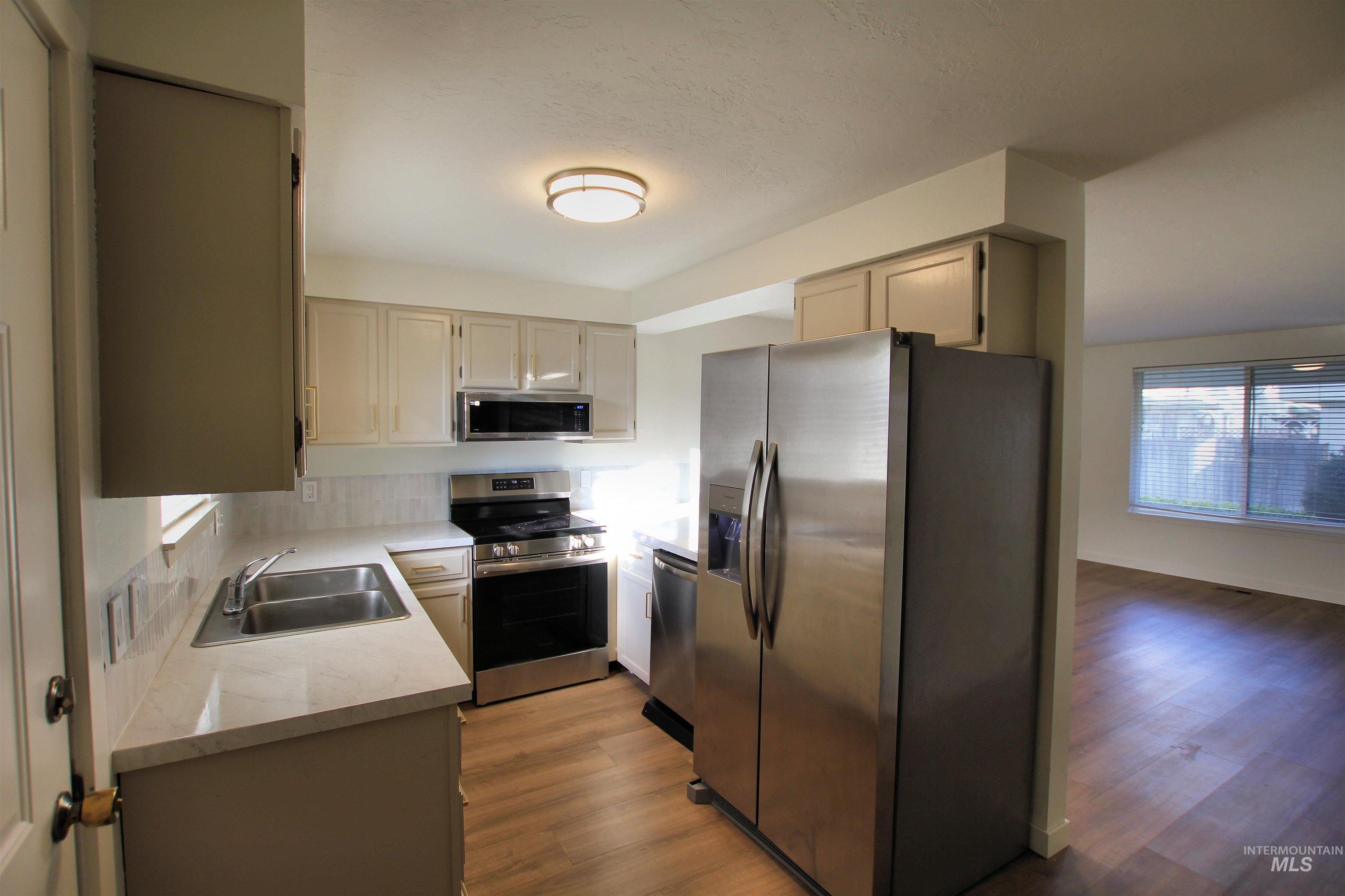 Kitchen featuring stainless steel appliances, light wood-style flooring, and decorative backsplash