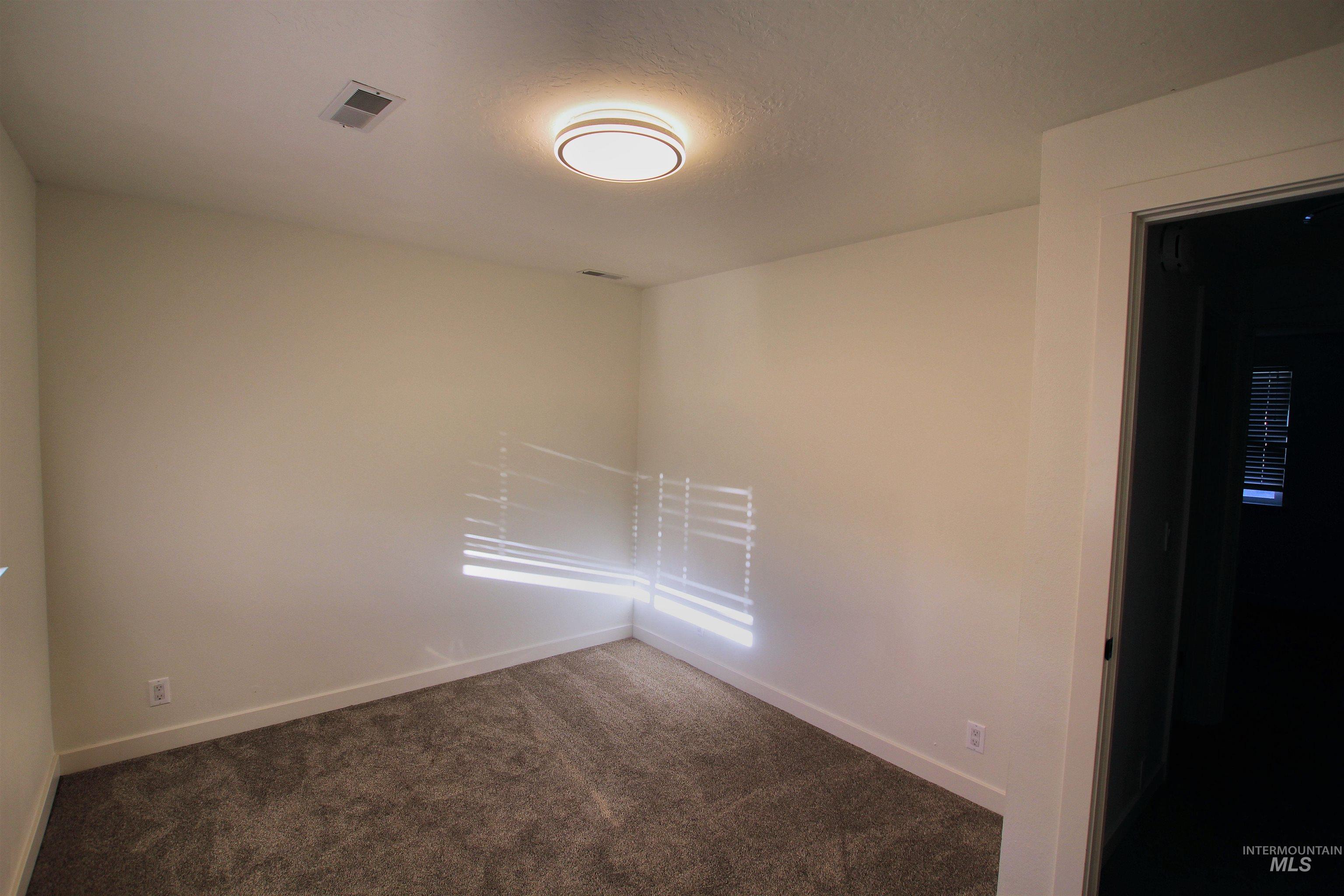 Unfurnished room featuring dark colored carpet and a textured ceiling