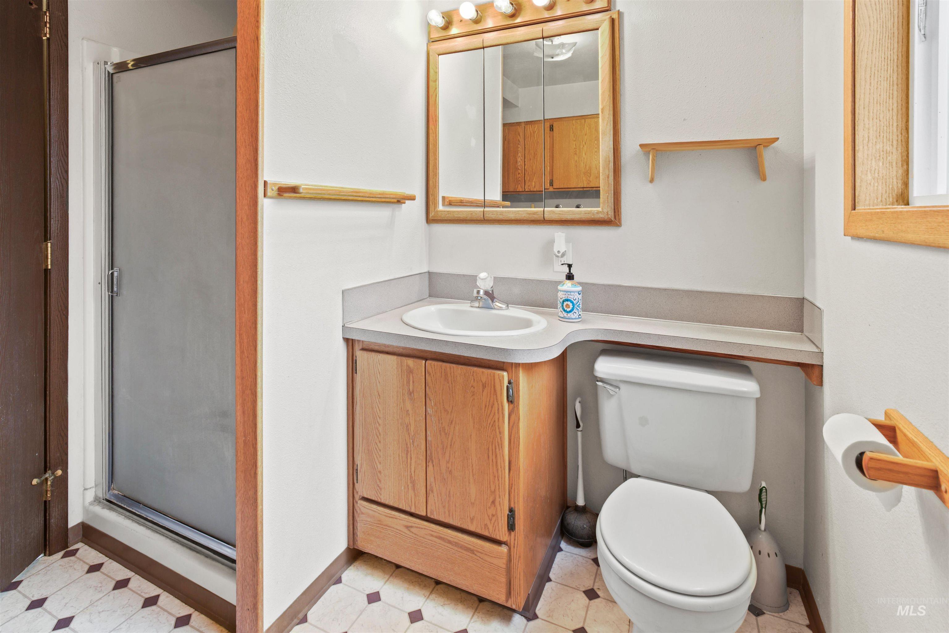 Full bathroom featuring a glass-enclosed shower, single vanity with wood cabinetry, and a mirrored medicine cabinet