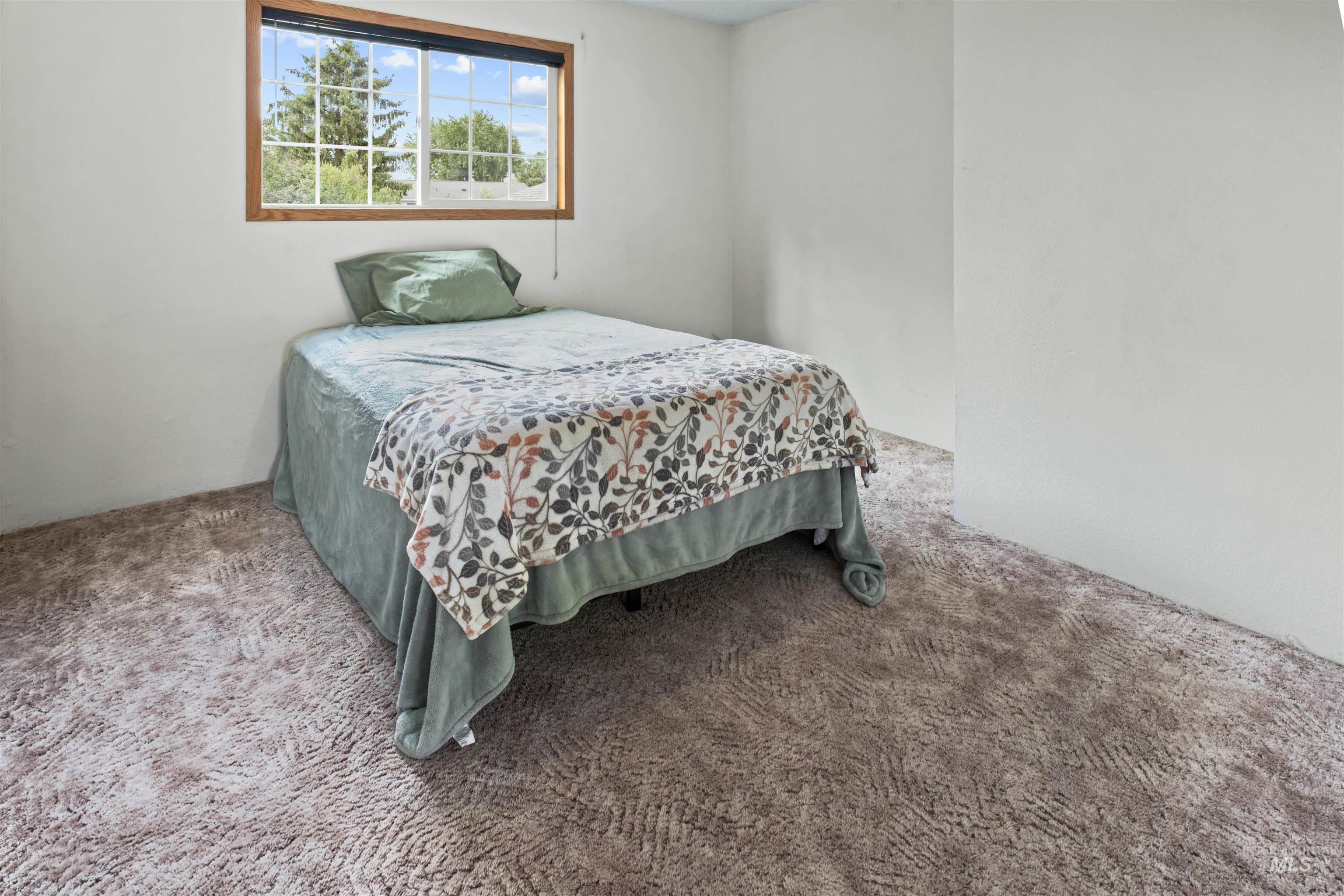 Room featuring a large window with wood trim, white walls, and patterned carpeting