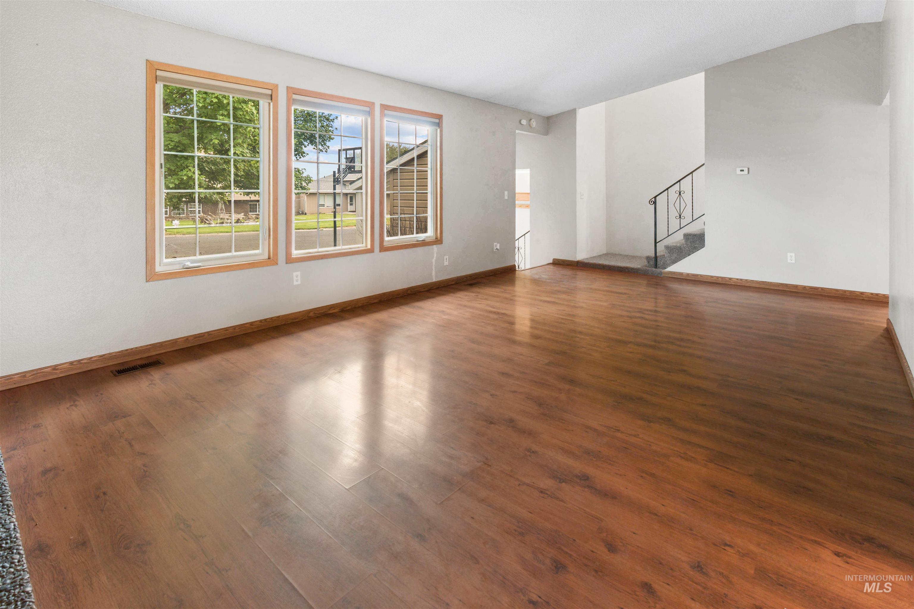 Expansive room featuring wood-finish flooring, light gray walls, and natural wood trim