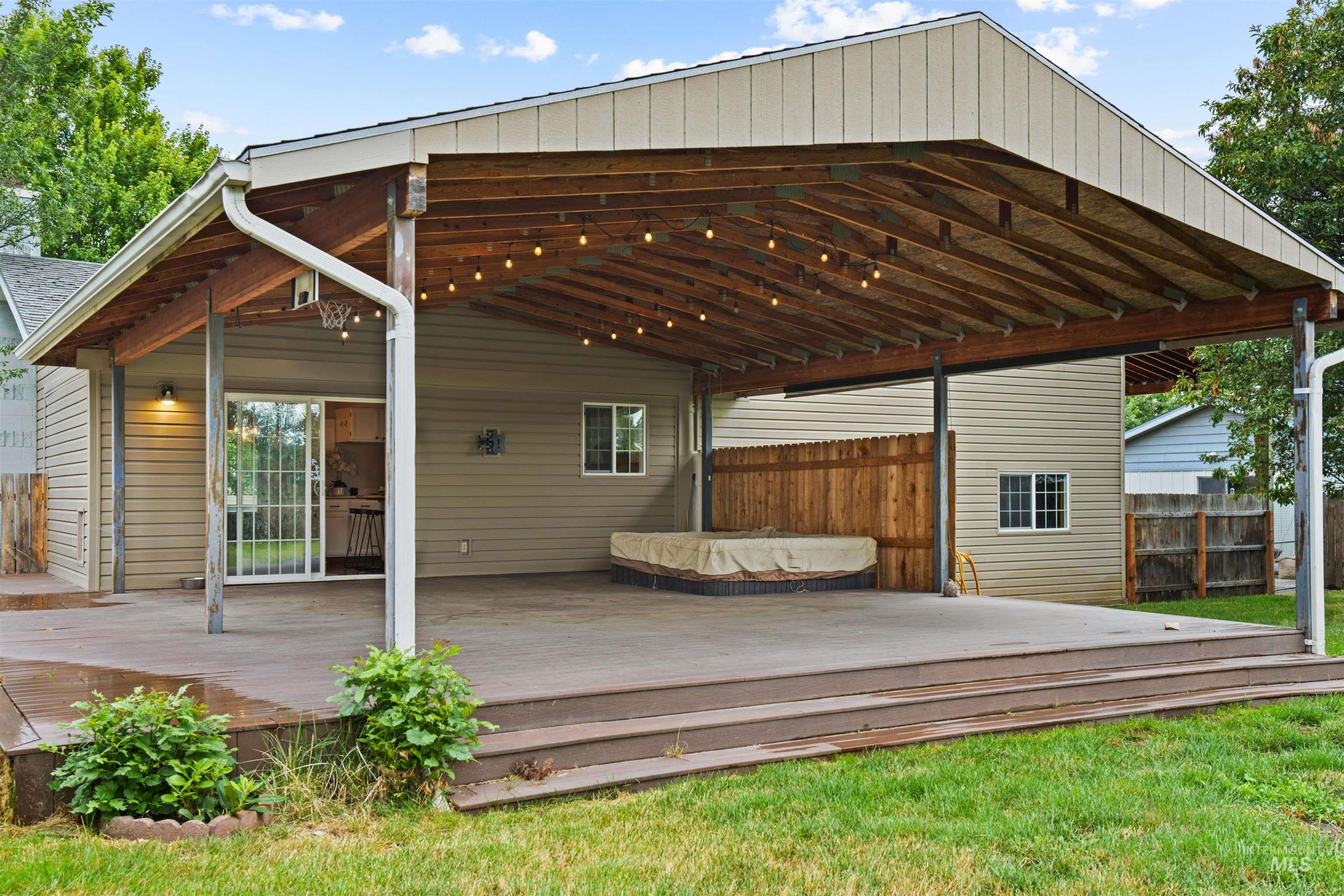 Expansive covered patio with exposed wood ceiling beams and string lighting