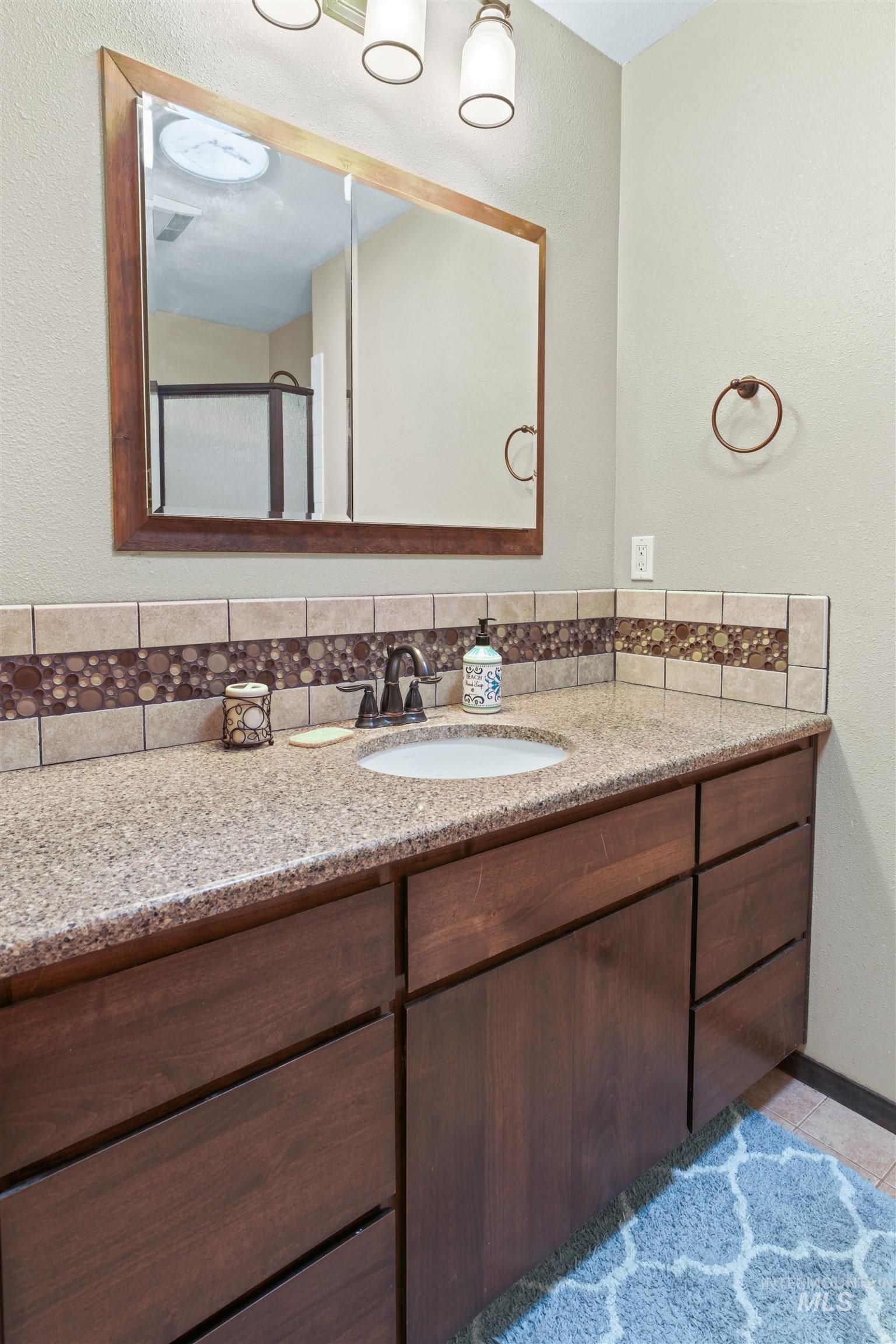 Bathroom vanity featuring a speckled countertop, integrated sink, and dark wood cabinetry with drawers