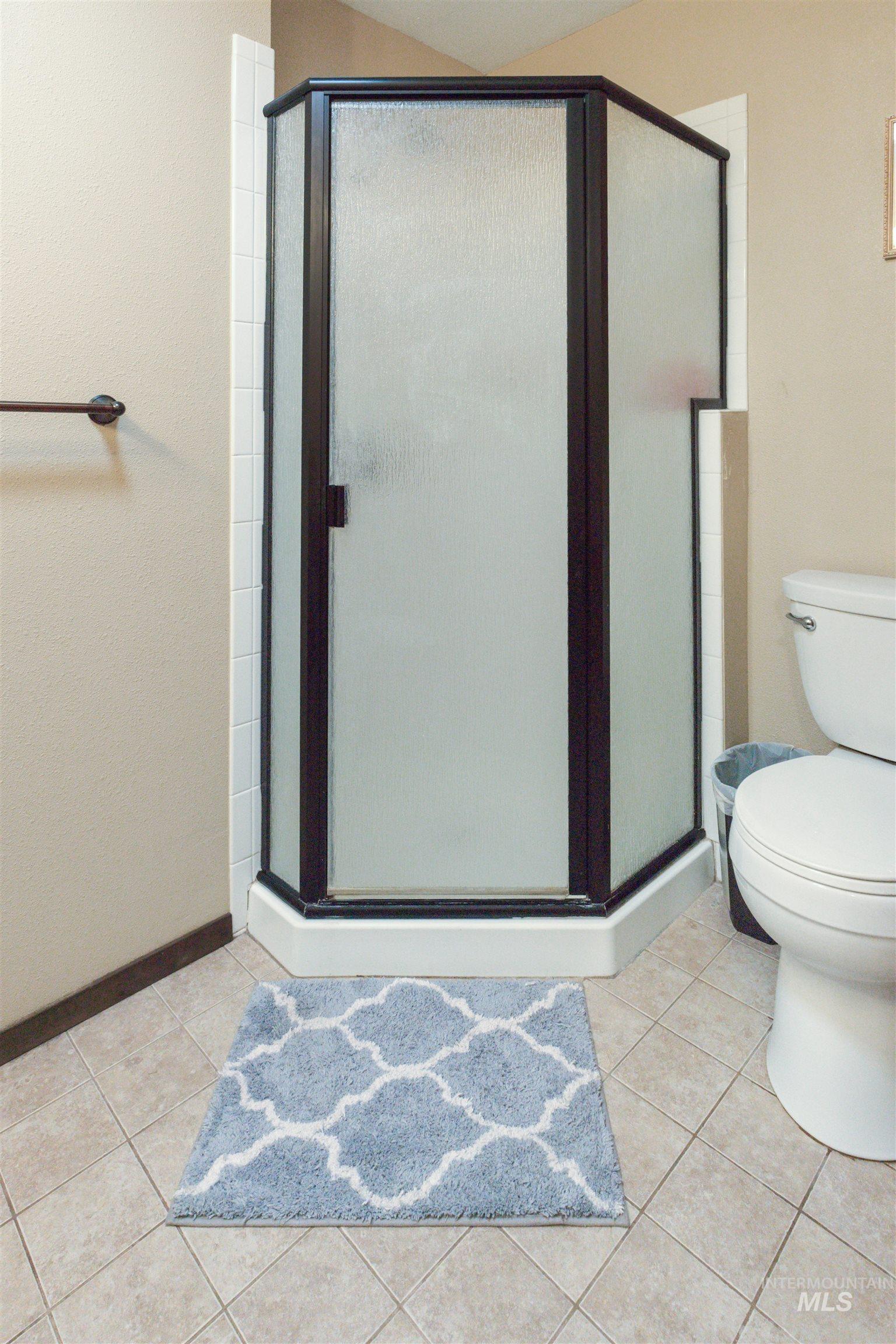 Corner shower enclosure with dark bronze framing and frosted glass panels