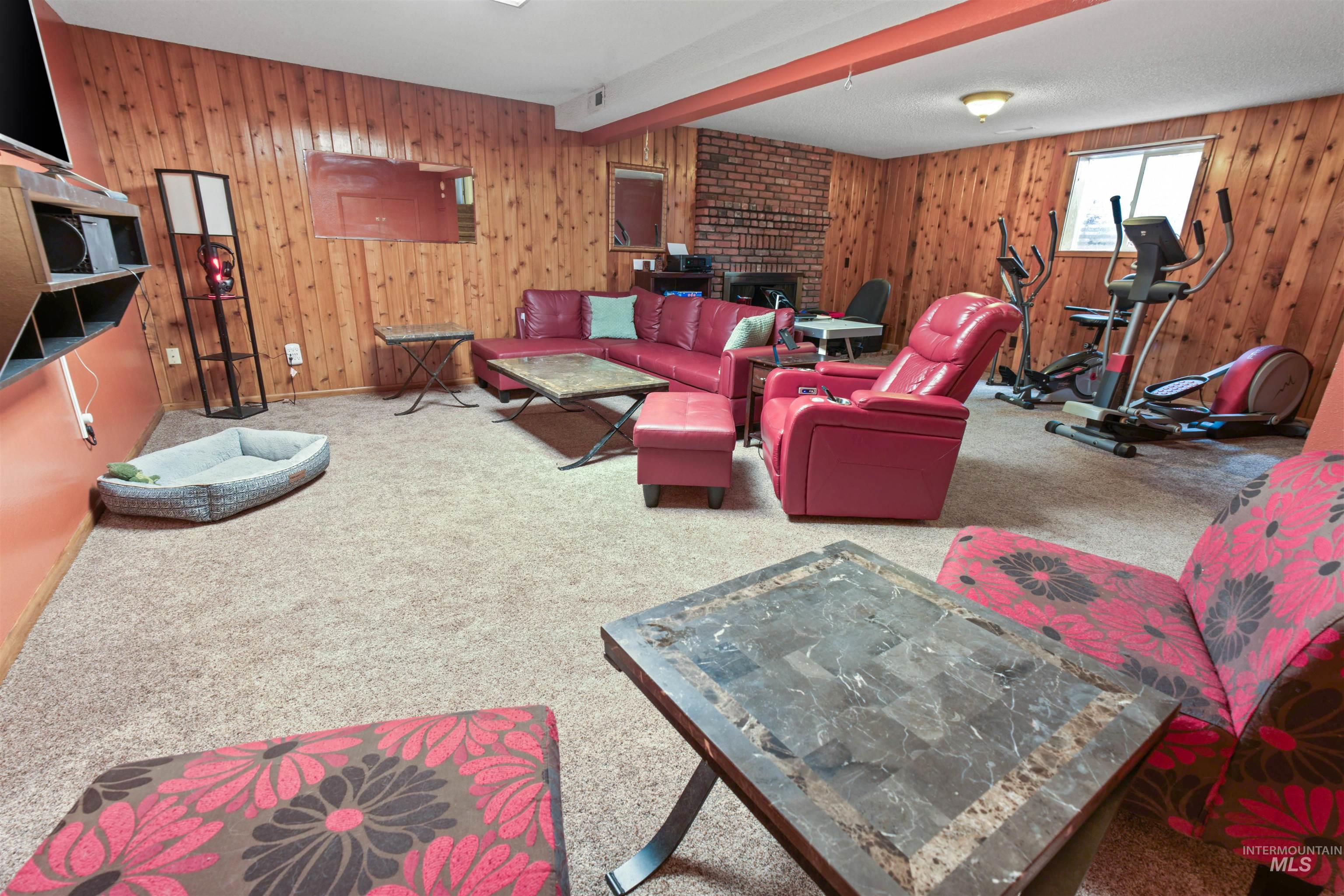 Carpeted lower level with wood paneling and exposed brick wall