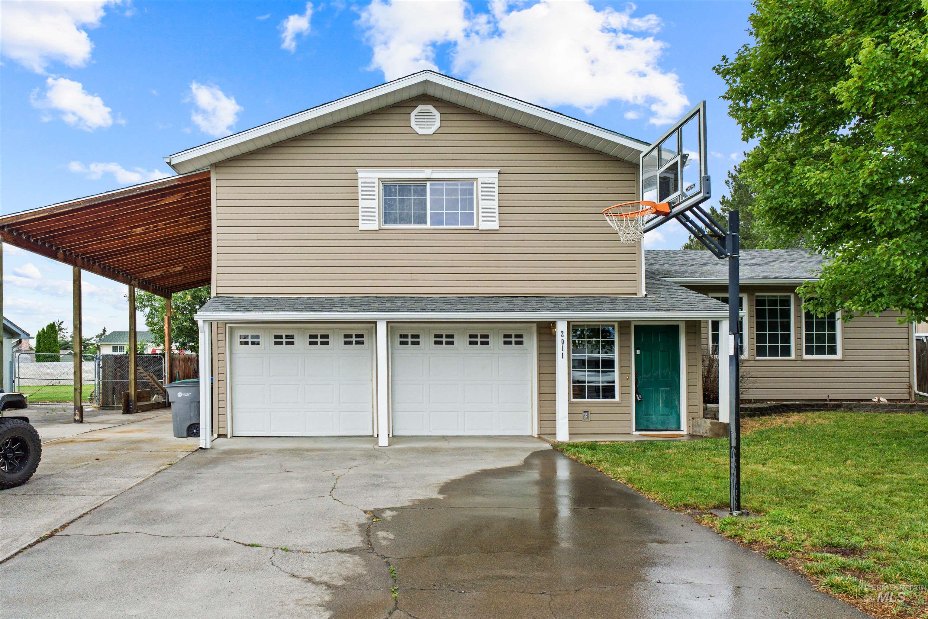 Two-story residence featuring tan siding and a dark green entry door