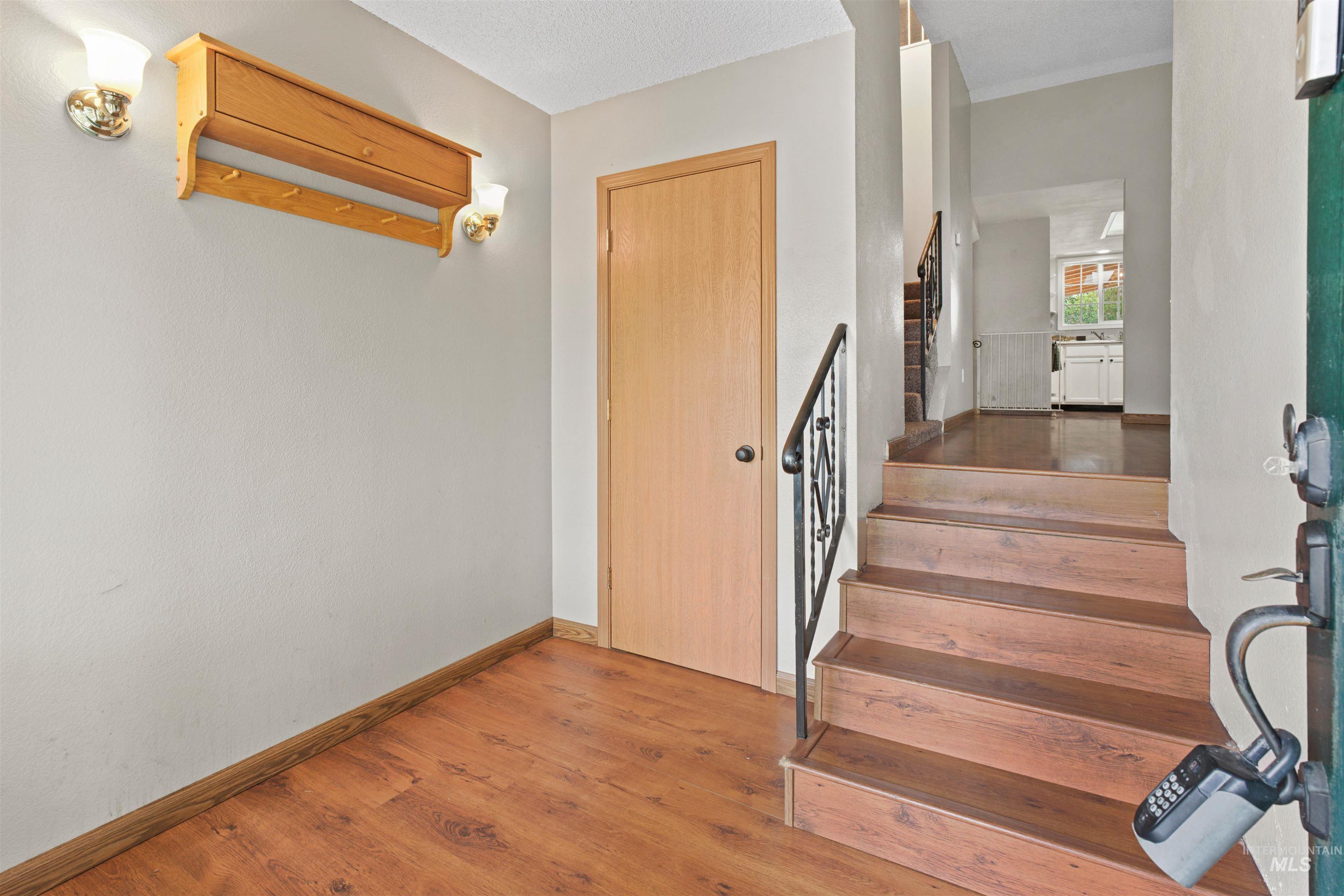 Entryway featuring wood-finish flooring, a staircase with a wrought iron railing, and a light wood door