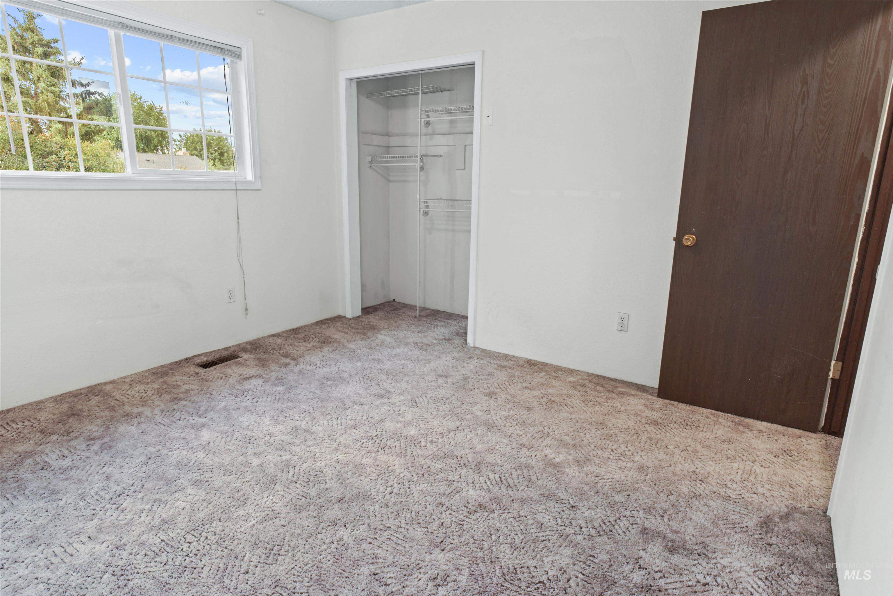 Room with patterned carpeting, white walls, and a window with white trim