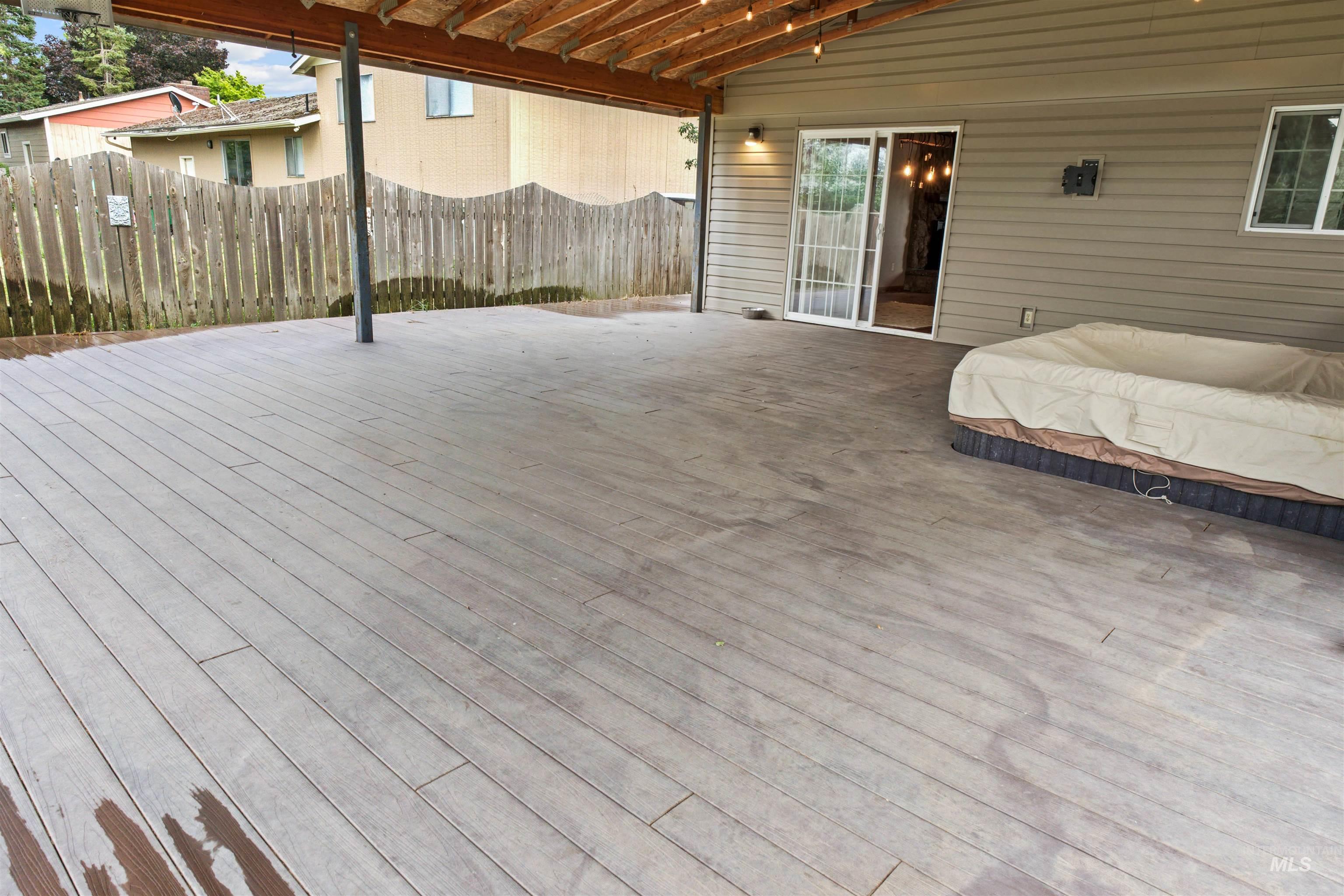 Expansive covered deck featuring composite decking and a built-in spa