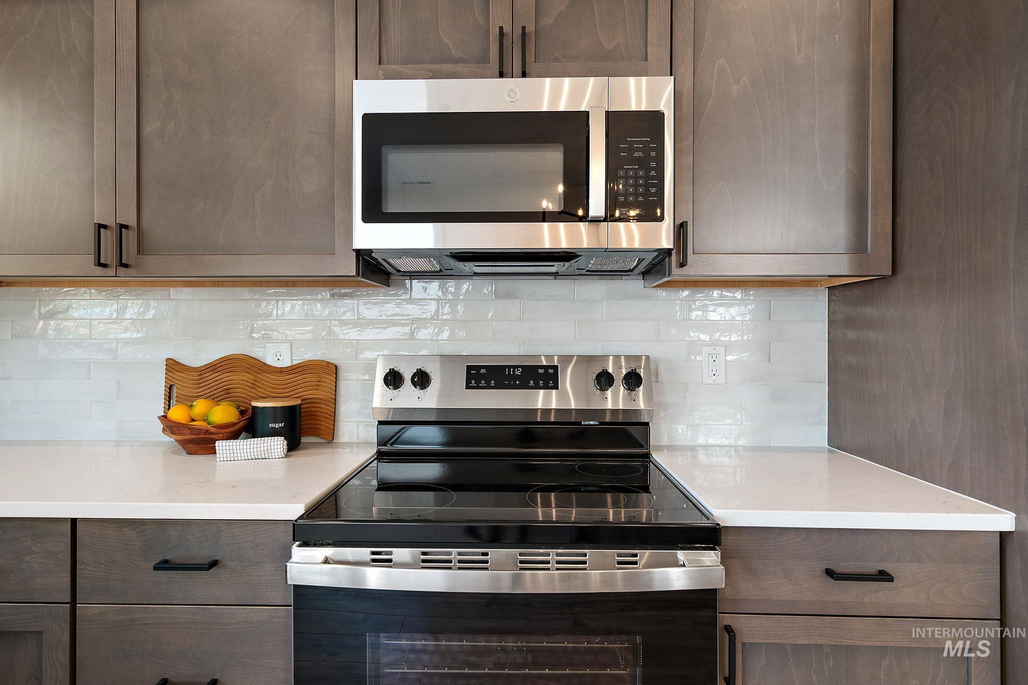 Kitchen featuring appliances with stainless steel finishes, decorative backsplash, light countertops, and dark brown cabinets