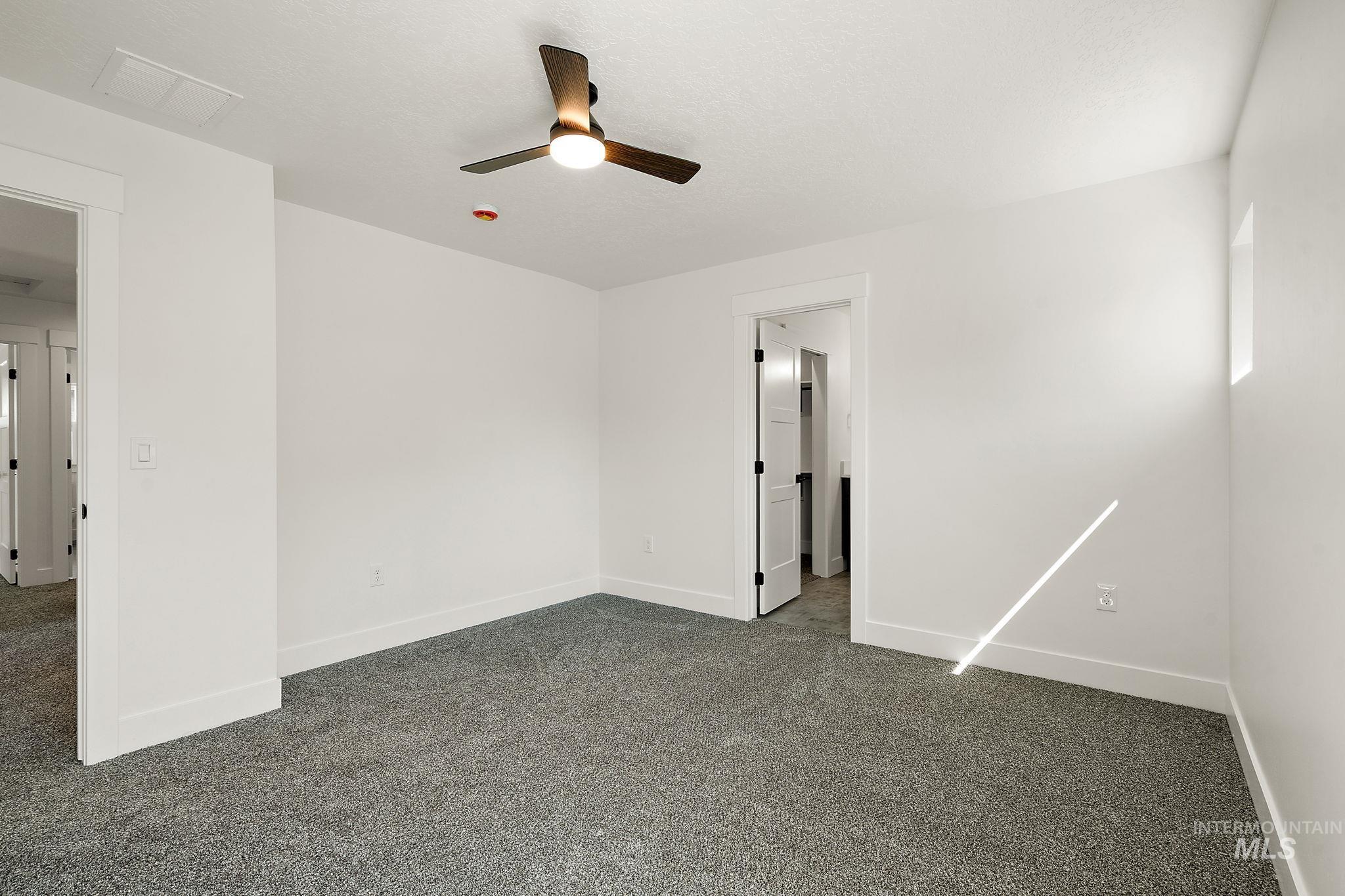 Spare room featuring a ceiling fan and dark colored carpet