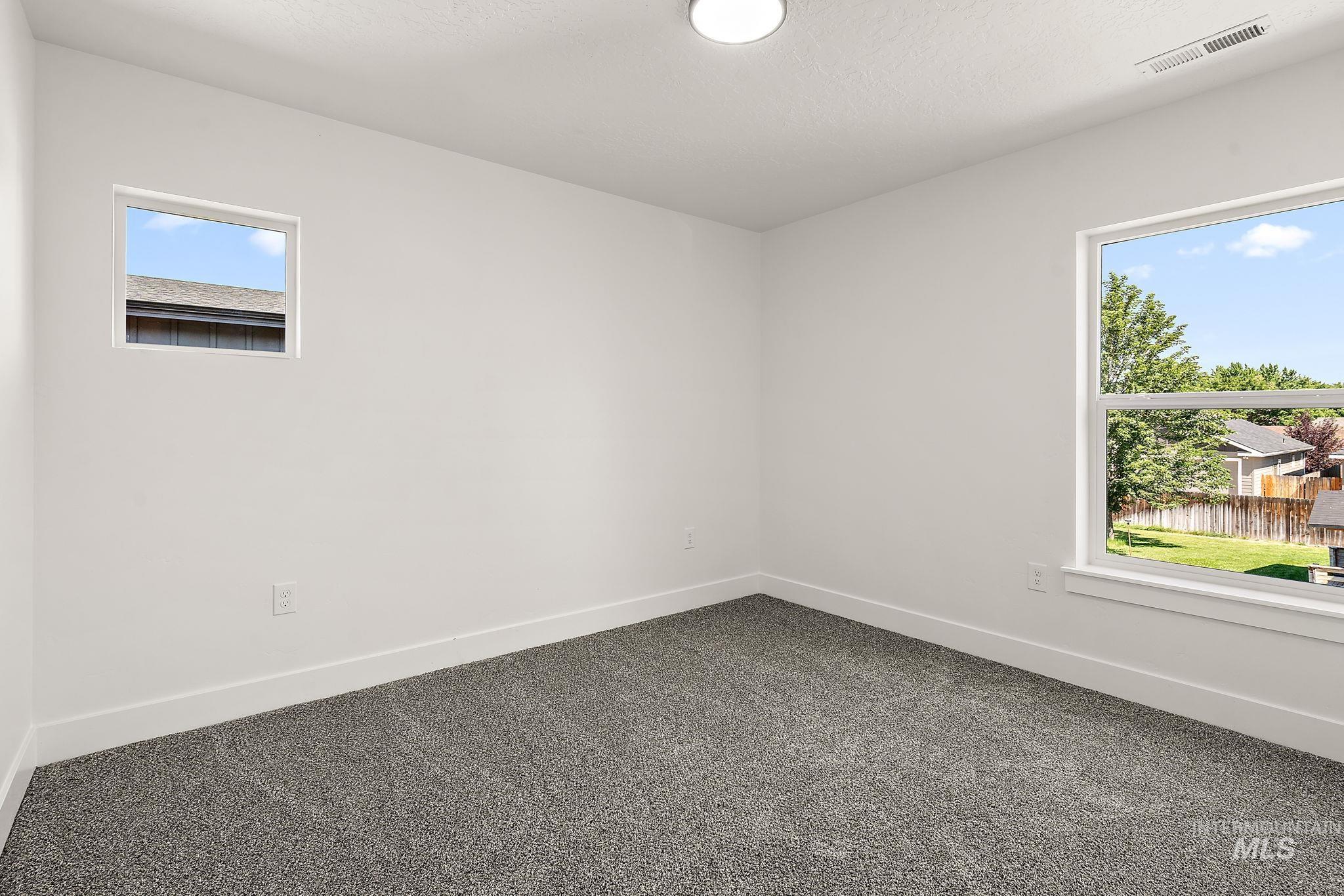 Spare room featuring healthy amount of natural light and dark carpet