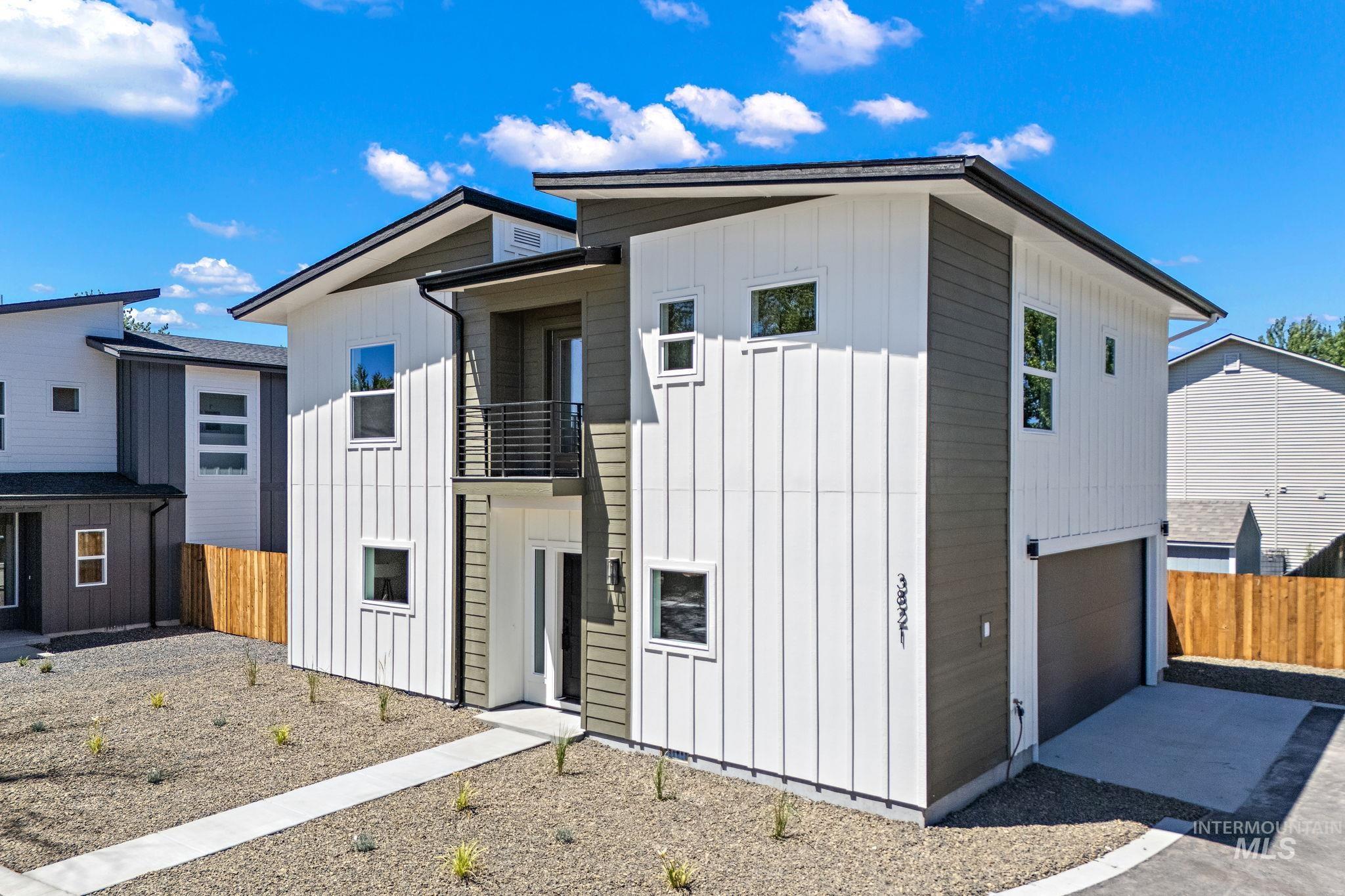 View of front of property featuring a balcony, a garage, board and batten siding, and driveway