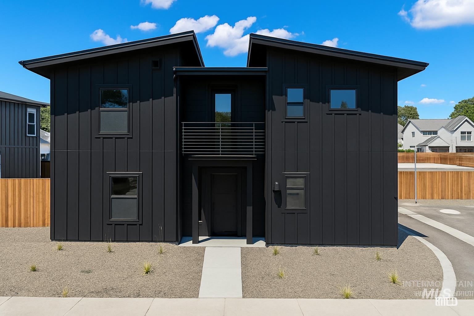 View of front of property with board and batten siding and a balcony