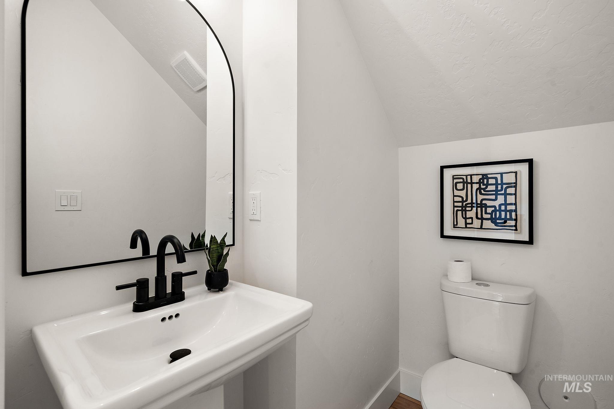 Bathroom featuring a sink and lofted ceiling