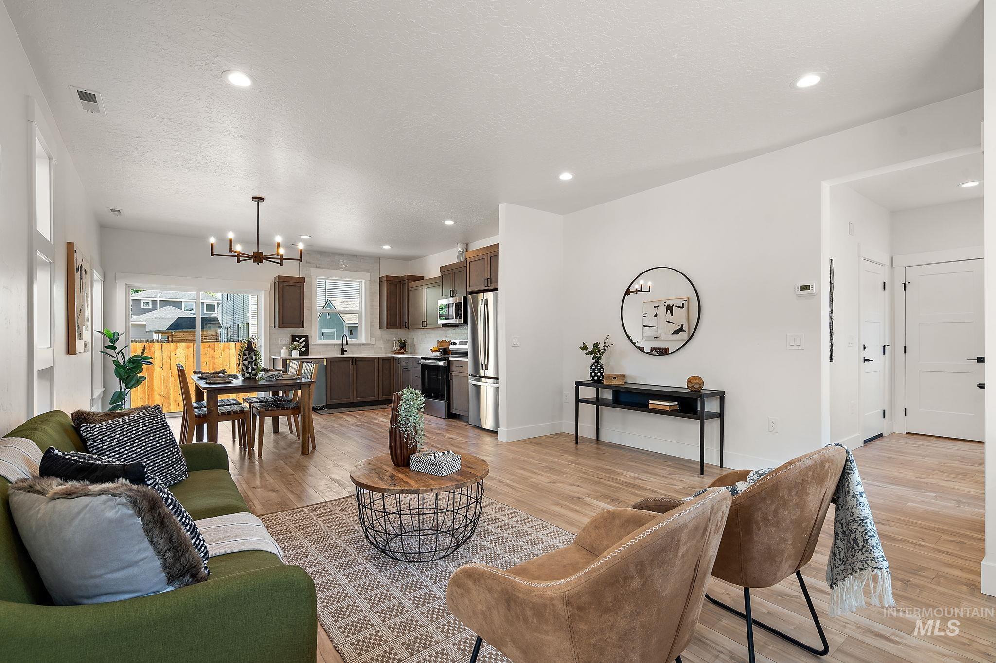 Living area with a chandelier, light wood-type flooring, recessed lighting, and a textured ceiling