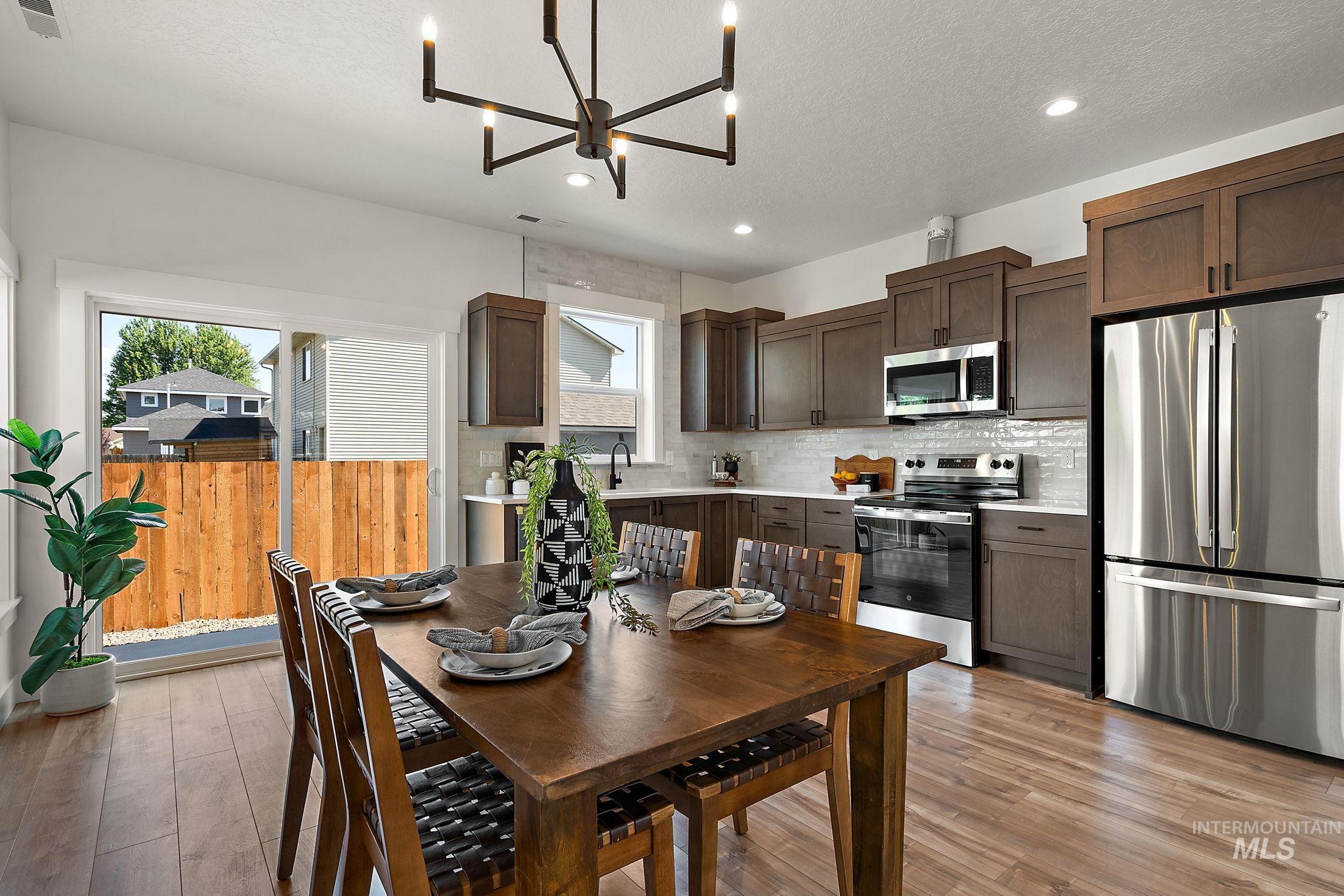 Dining area with a chandelier, healthy amount of natural light, recessed lighting, light wood finished floors, and a textured ceiling
