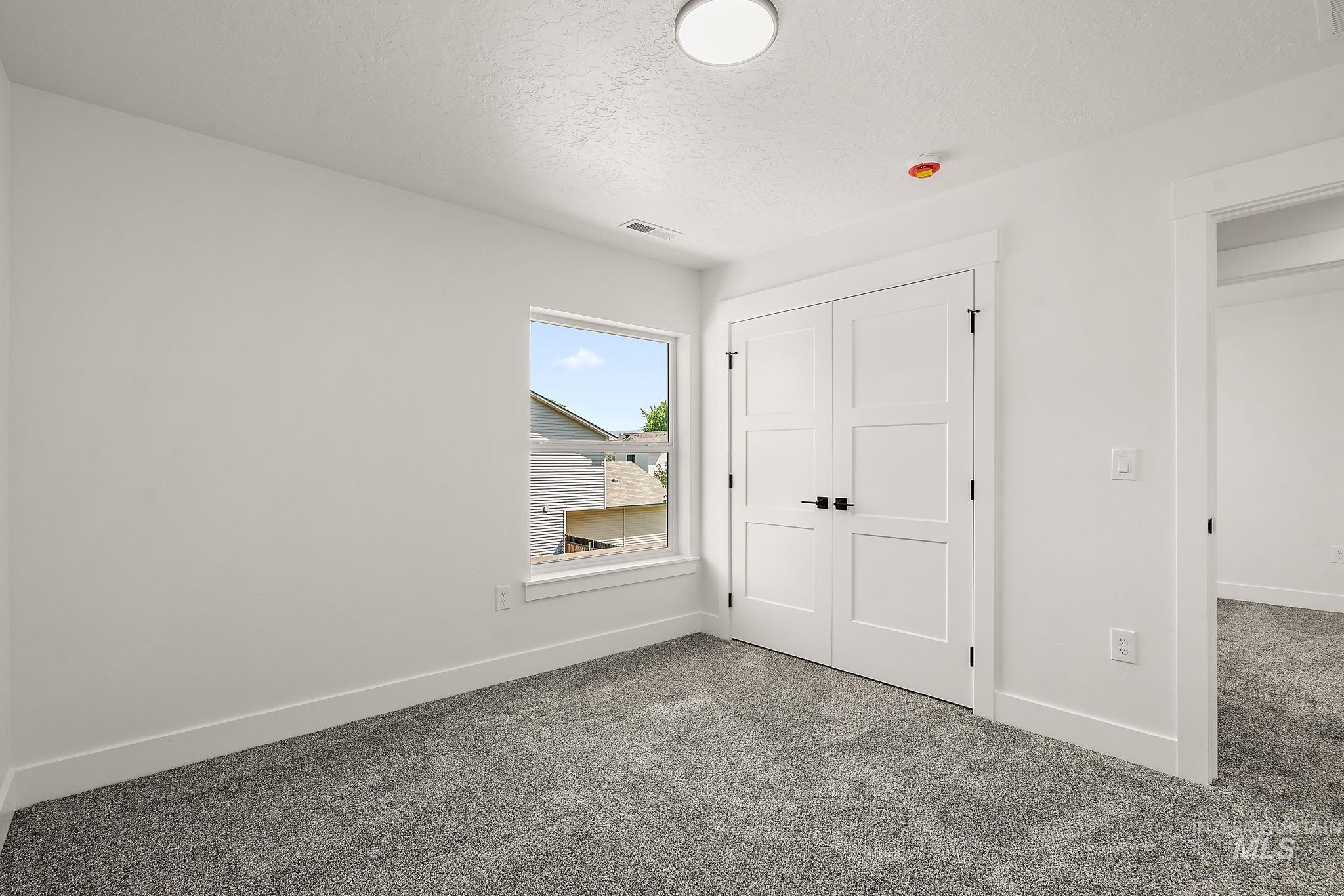 Unfurnished bedroom with a textured ceiling, carpet flooring, and a closet