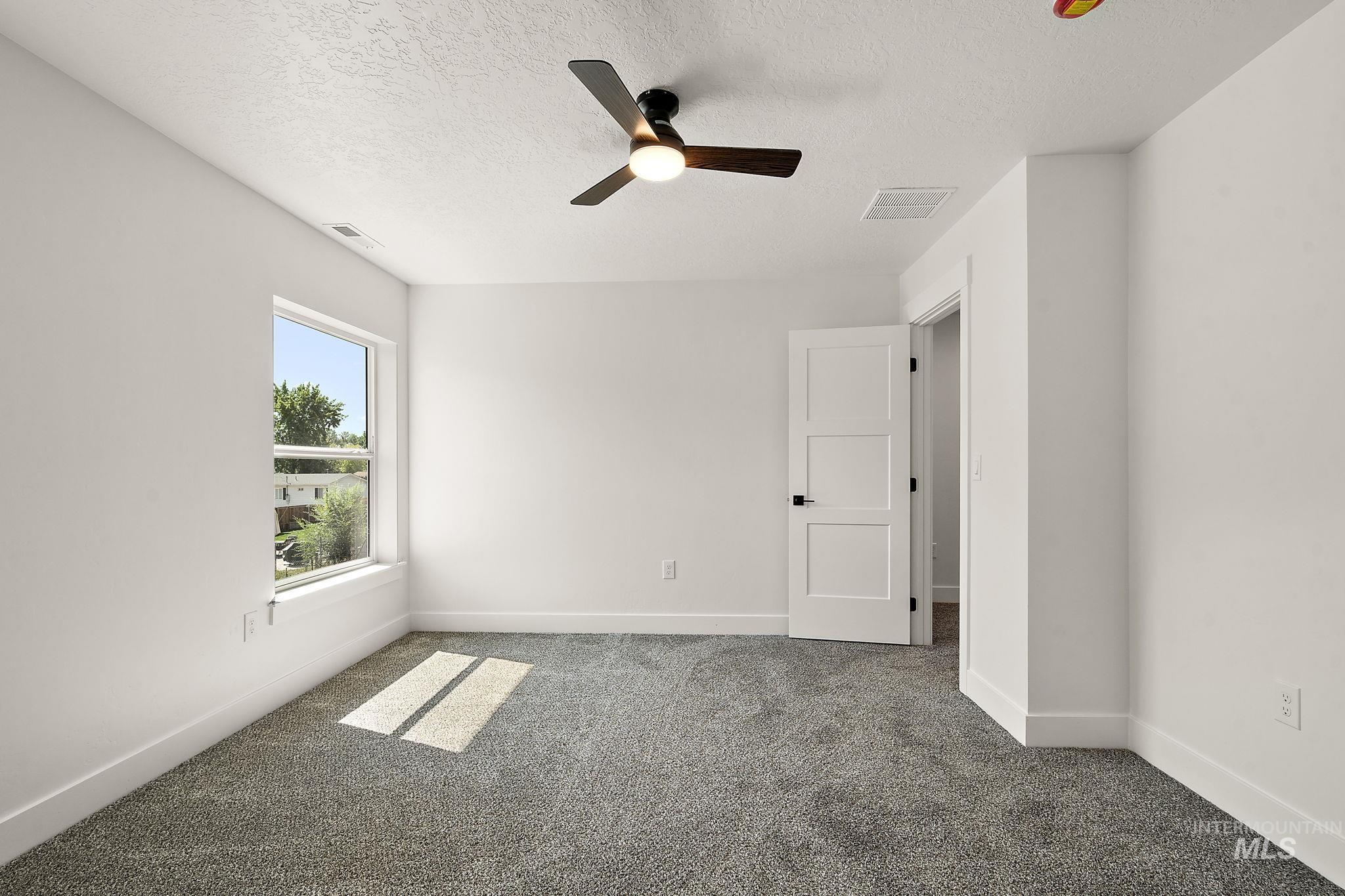 Carpeted empty room featuring a ceiling fan and a textured ceiling