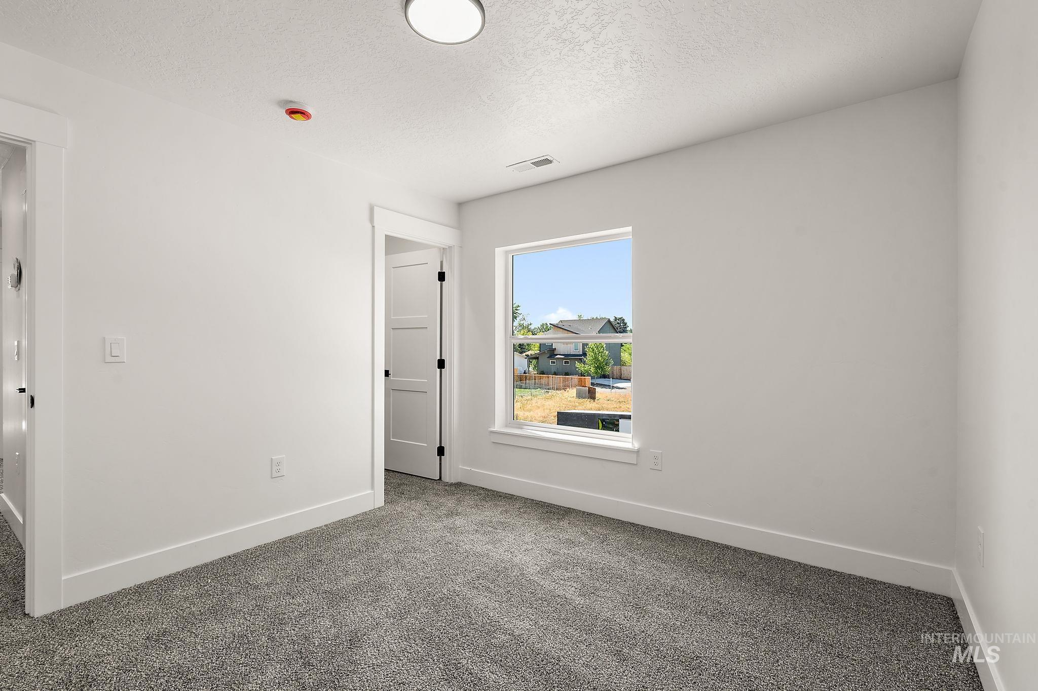 Empty room with carpet flooring and a textured ceiling