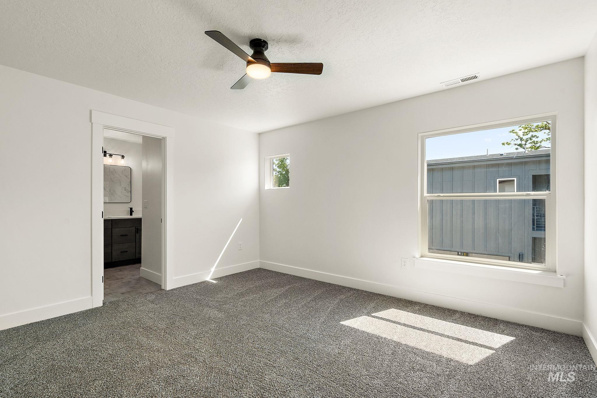 Carpeted spare room with ceiling fan and a textured ceiling