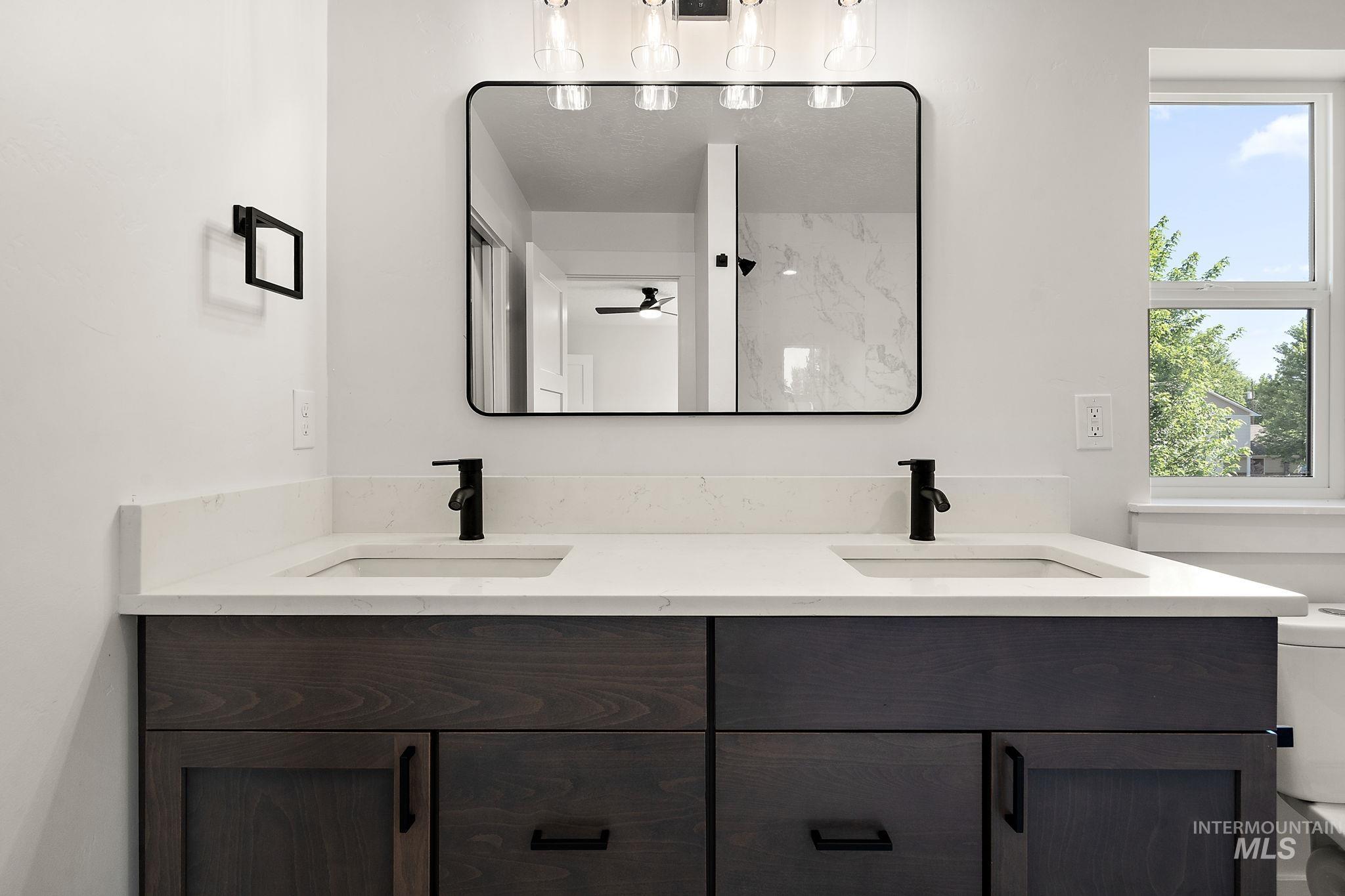 Bathroom with double vanity, ceiling fan, and a shower
