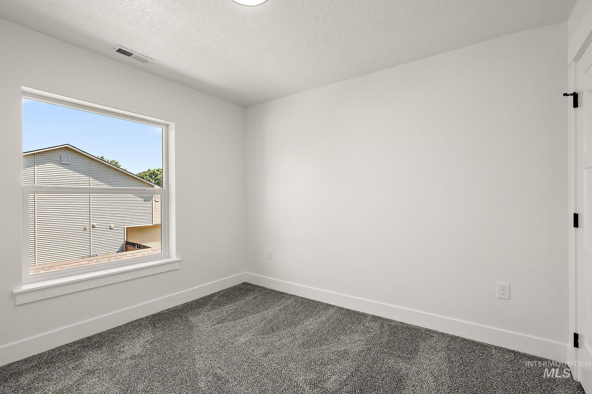 Unfurnished room with dark carpet and a textured ceiling