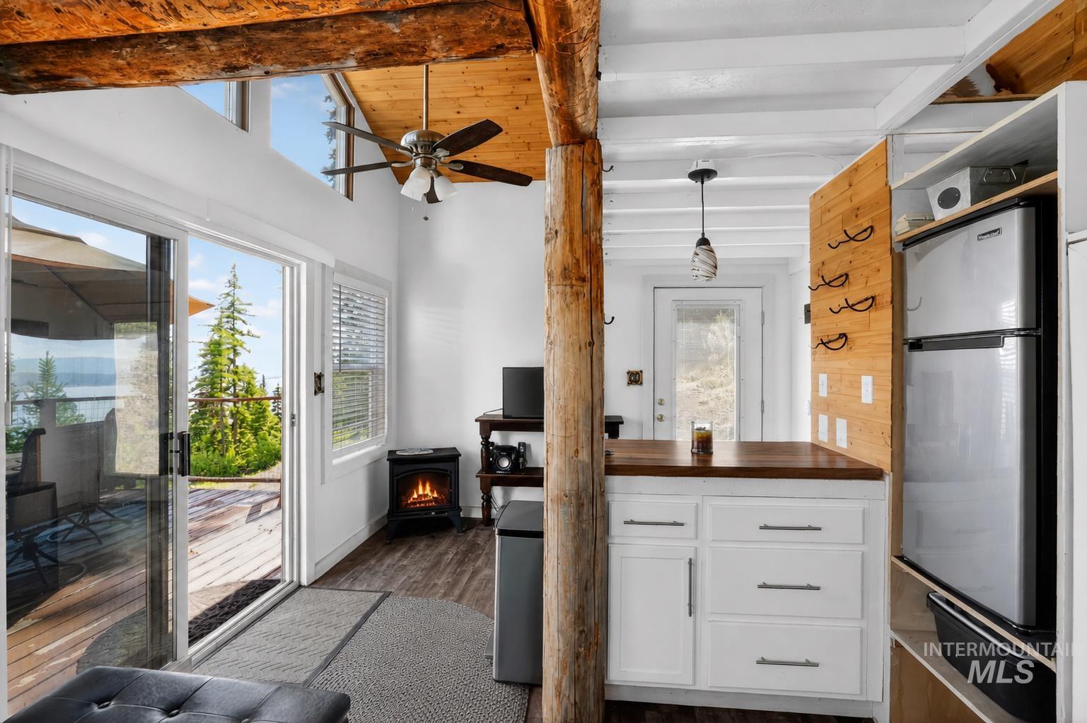 Interior space featuring wood-finish flooring, exposed wood beams, and a vaulted ceiling with a ceiling fan