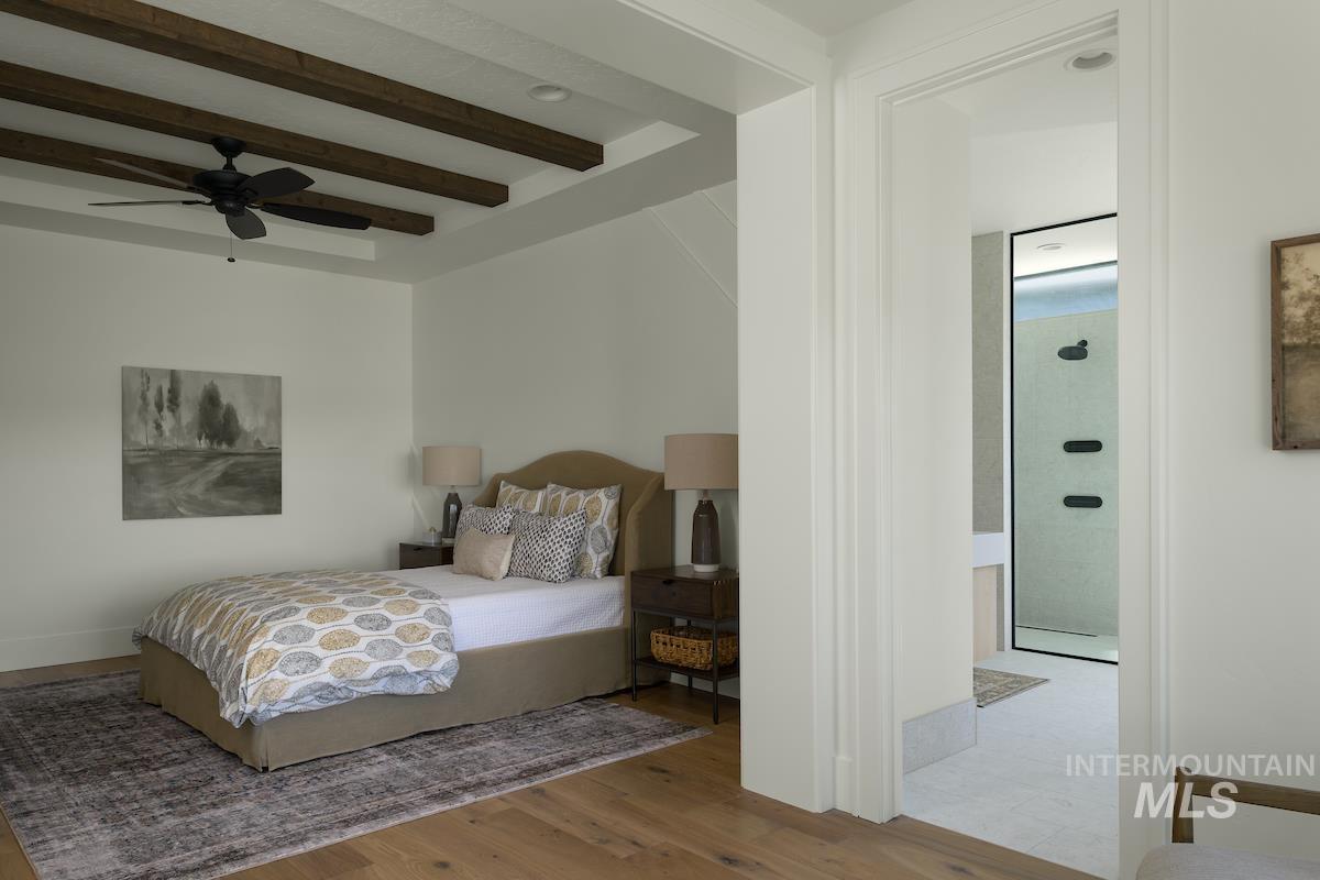Bedroom featuring beam ceiling, wood finished floors, and ceiling fan
