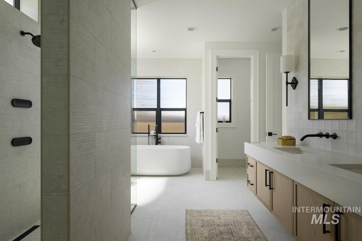 Bathroom featuring plenty of natural light, a tile shower, a freestanding bath, double vanity, and tile walls