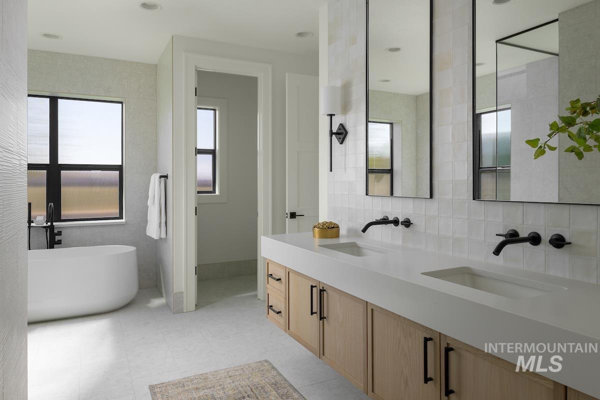 Full bathroom featuring a freestanding bath, double vanity, and tile walls