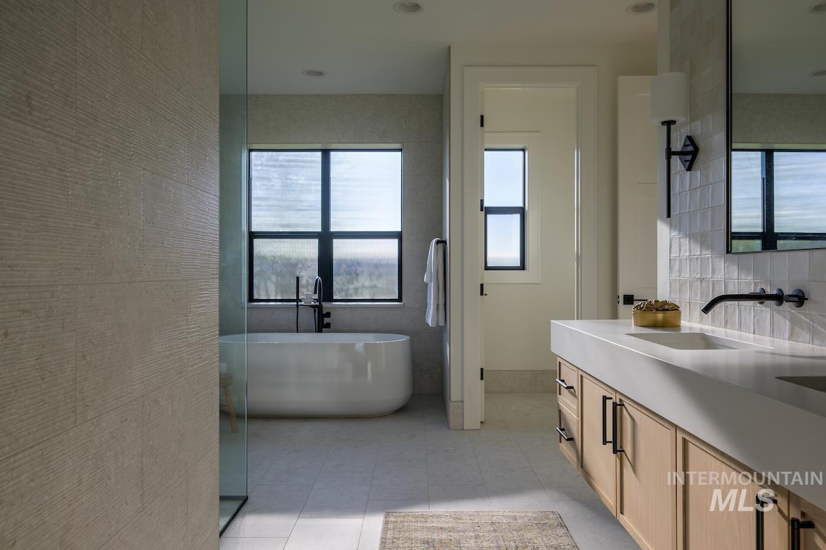 Bathroom with plenty of natural light, vanity, a soaking tub, tile patterned floors, and tile walls