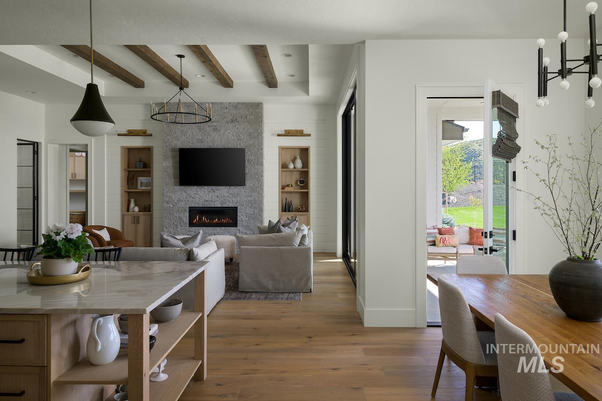 Dining space featuring wood finished floors, beamed ceiling, built in features, a large fireplace, and a chandelier