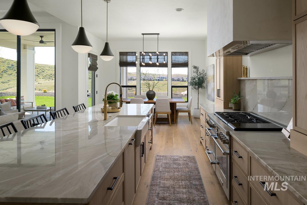 Kitchen with plenty of natural light, double oven range, premium range hood, and light stone countertops