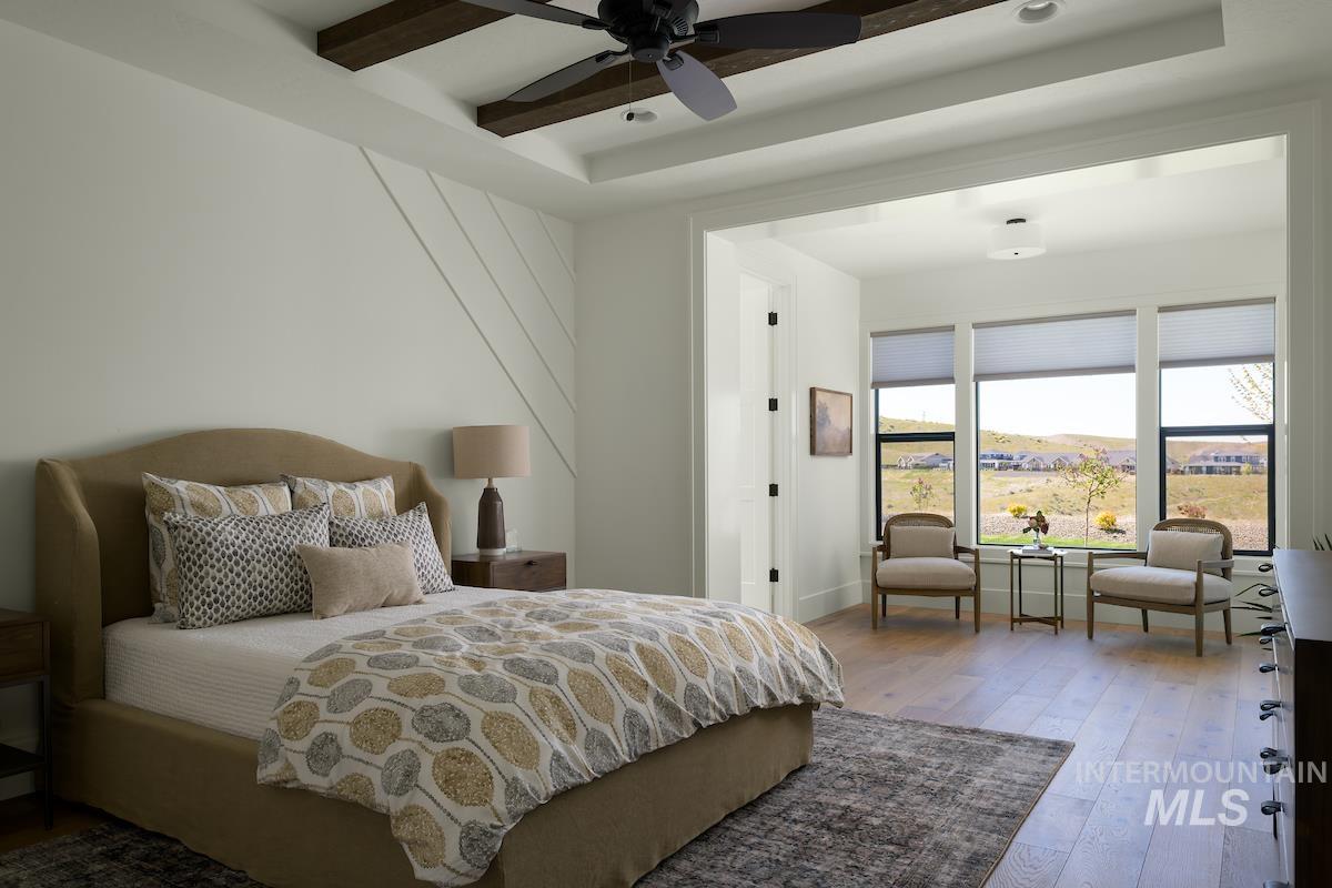 Bedroom with hardwood / wood-style floors, a raised ceiling, a ceiling fan, and beamed ceiling