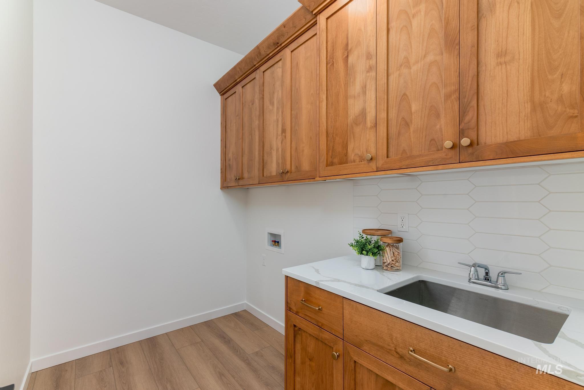 Laundry area featuring hookup for a washing machine, light wood-style flooring, and cabinet space