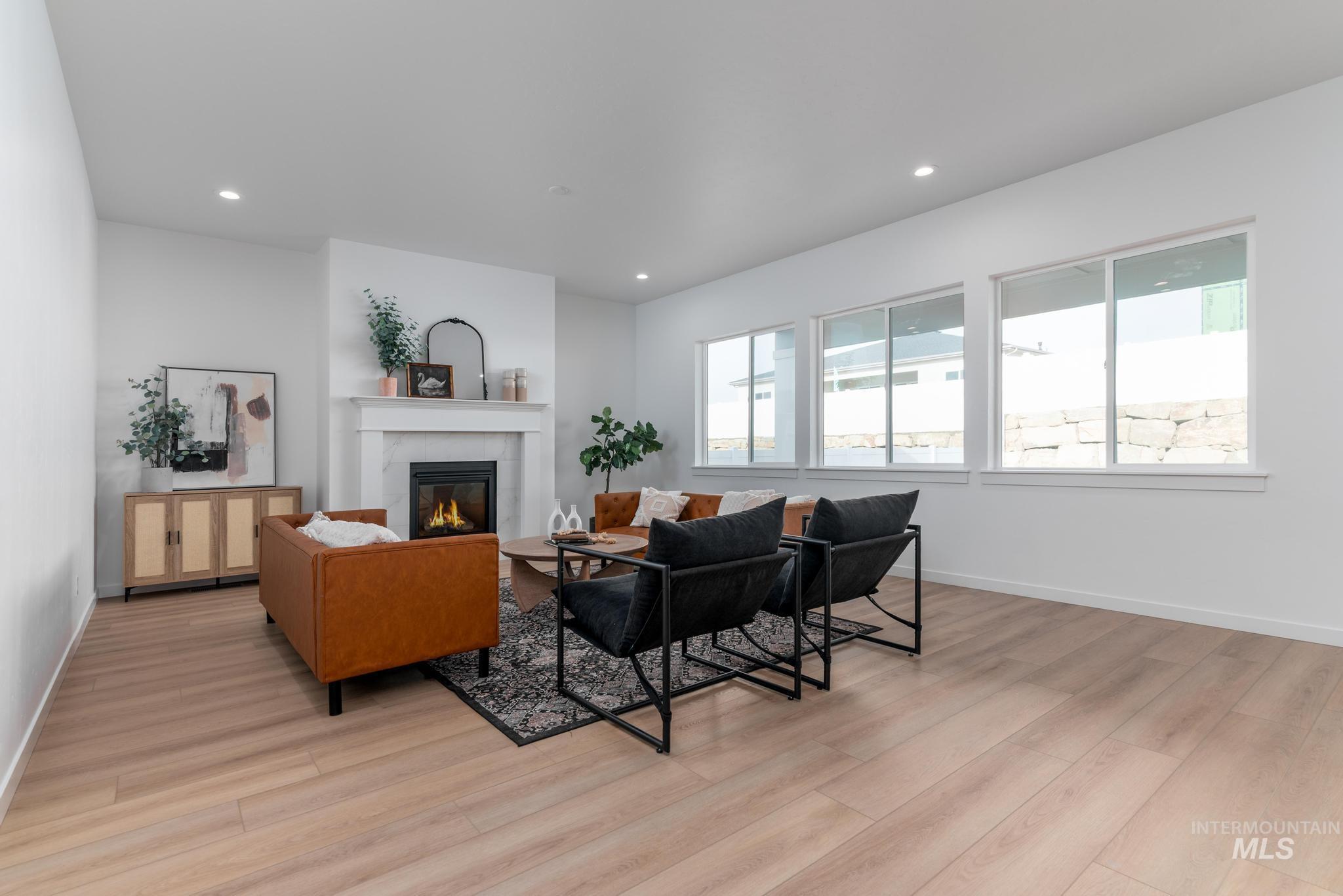 Living area featuring a glass covered fireplace, light wood-style floors, and recessed lighting