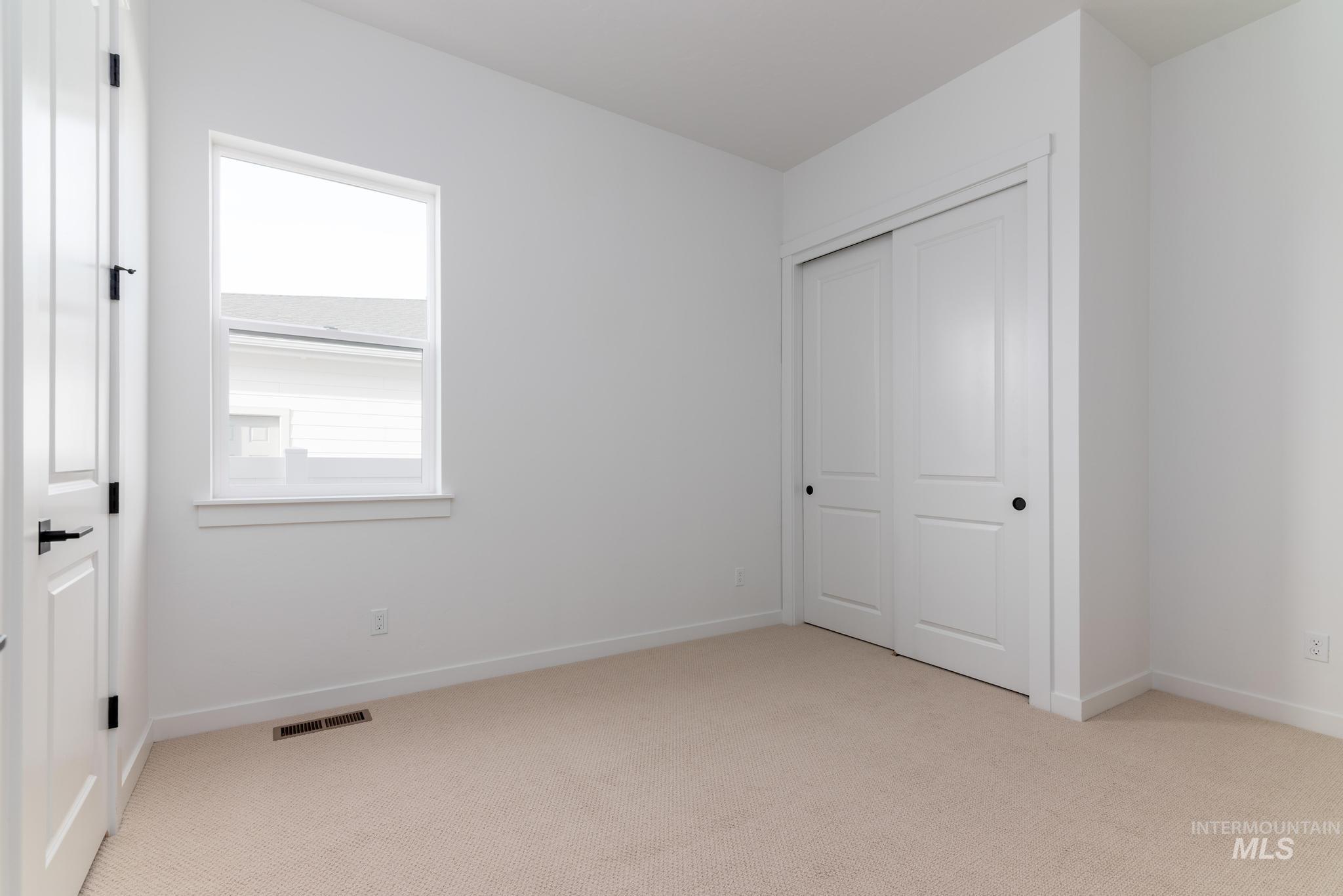 Unfurnished bedroom with light carpet and a closet