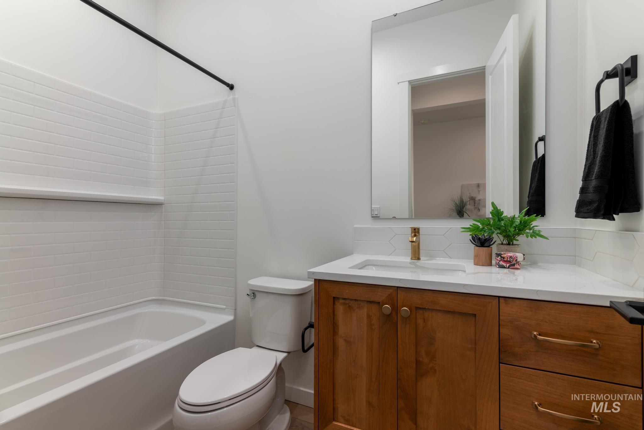 Full bathroom featuring vanity, shower / washtub combination, and tasteful backsplash