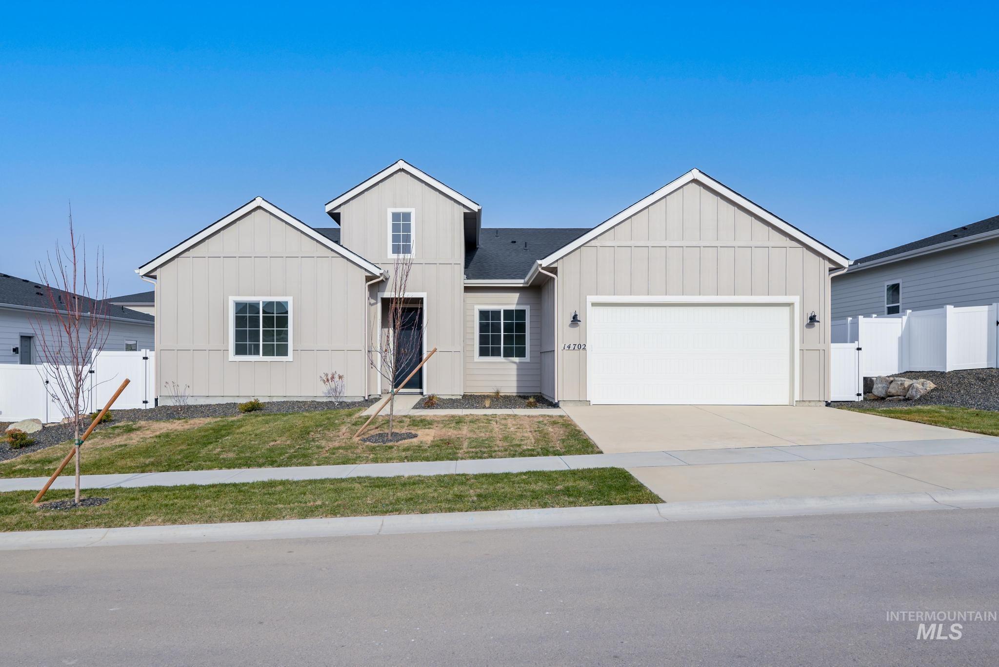 View of front of home with board and batten siding, concrete driveway, an attached garage, and a gate