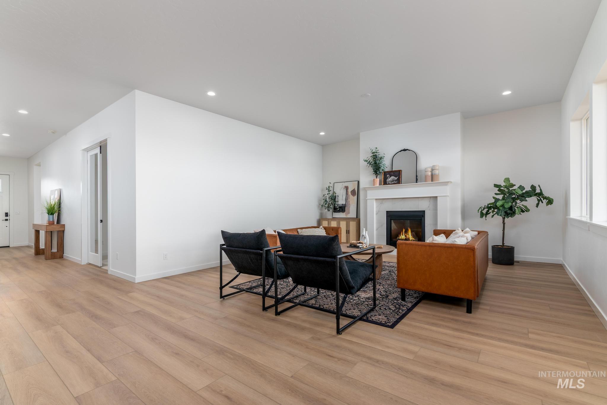 Living room featuring recessed lighting, a tile fireplace, and light wood-style flooring